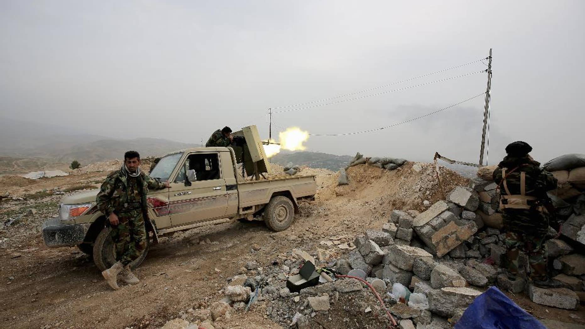 Jan. 29, 2015: In this file photo, a Kurdish peshmerga fighter fires a weapon towards positions of the Islamic State group who are 500 meters or half a mile away, overlooking the strategic town of Sinjar, northern Iraq. While Islamic State fighters have been forced to retreat from Kobani, the strategic town on Syria’s border with Turkey, they appear far from beaten in northern Iraq.