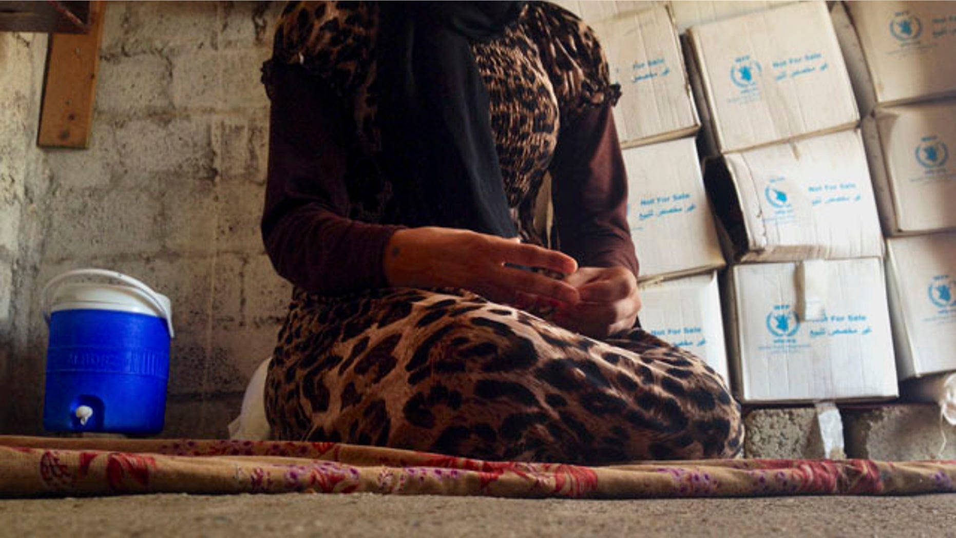 FILE - In this file photo taken Wednesday, Oct. 8, 2014, a 15-year-old Yazidi girl captured by ISIS and forcibly married to a militant in Syria sits on the floor of a one-room house she now shares with her family after escaping in early August, while speaking in an interview with The Associated Press in Maqluba, a hamlet near the Kurdish city of Dahuk, 260 miles northwest of Baghdad. (AP Photo/Dalton Bennett, File)