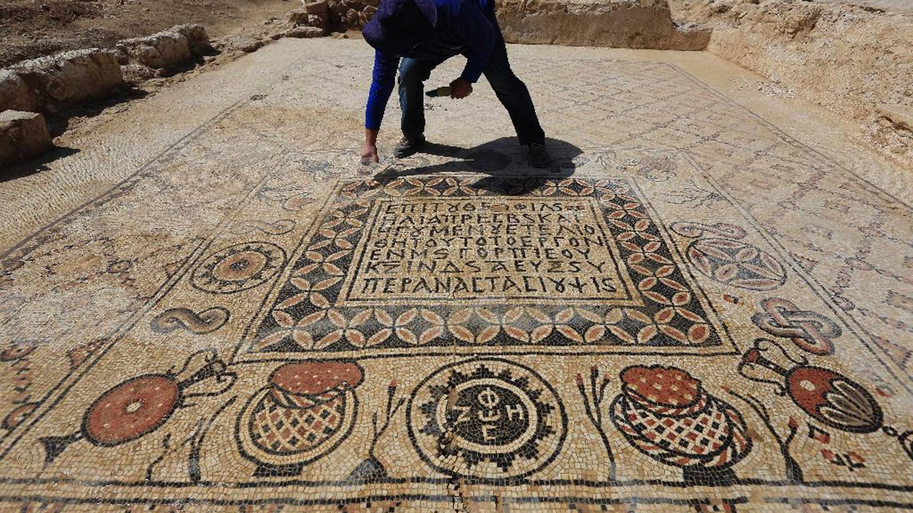 An Israeli Antiquities Authority archeologist Daniel Varge works on a Byzantine period monastery mosaic near a village of Hura, Tuesday, April 1, 2014. Israel's Antiquities Authority has unveiled a monastery dating back about 1,400 years in the south of the country with an impressive mosaic floors that shed light on life in the region during the Byzantine period. (AP Photo/Tsafrir Abayov)