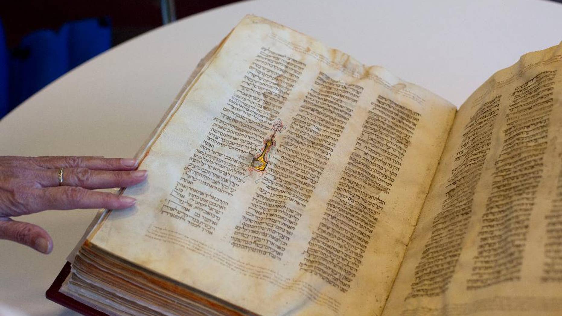FILE - In this Oct. 5, 2014 file photo, a library official shows a Jewish manuscript smuggled into Israel from Damascus in a Mossad spy operation in the early 1990s, in Jerusalem. The manuscript is one of the earliest existing complete manuscripts of the Hebrew bible. Two decades after Israeli spies helped whisk eight ancient Hebrew bibles from Damascus to Jerusalem, Israel’s national library asked an Israeli court Monday, Dec. 8, 2014 to grant it official custodianship over the manuscripts, a move that is liable to spark a bitter ownership battle over the some of the Syrian Jewish community’s most important treasures. (AP Photo/Sebastian Scheiner, File)