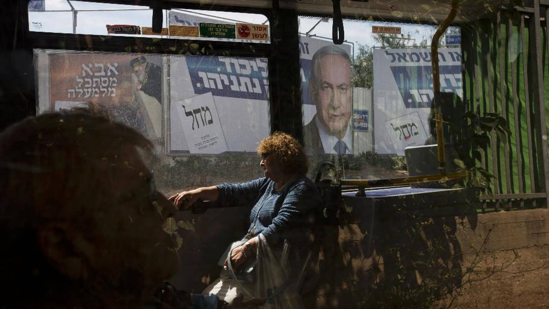 FILE - In this Monday, March 16, 2015 file photo, passengers sit in a bus driving past a billboard with the photo of Israeli Prime Minister Benjamin Netanyahu, right, and late rabbi Ovadia Yosef, a long time spiritual leader of the Shas party, a day ahead of legislative elections, in Bnei Brak near Tel Aviv, Israel. The displeasure felt in some quarters over Netanyahu's win last week has placed front and center the world community's unwritten obligation to accept the results of a truly democratic vote. It is a basic tenet of the modern world order which has survived the occasional awkward result _ as well as recent decades' emergence of some less-than-pristine democracies around the globe. The Hebrew sign at left reads, " Father is looking from above.'' At right Hebrew reads, "Likud, Netanyahu." (AP Photo/Ariel Schalit, File)