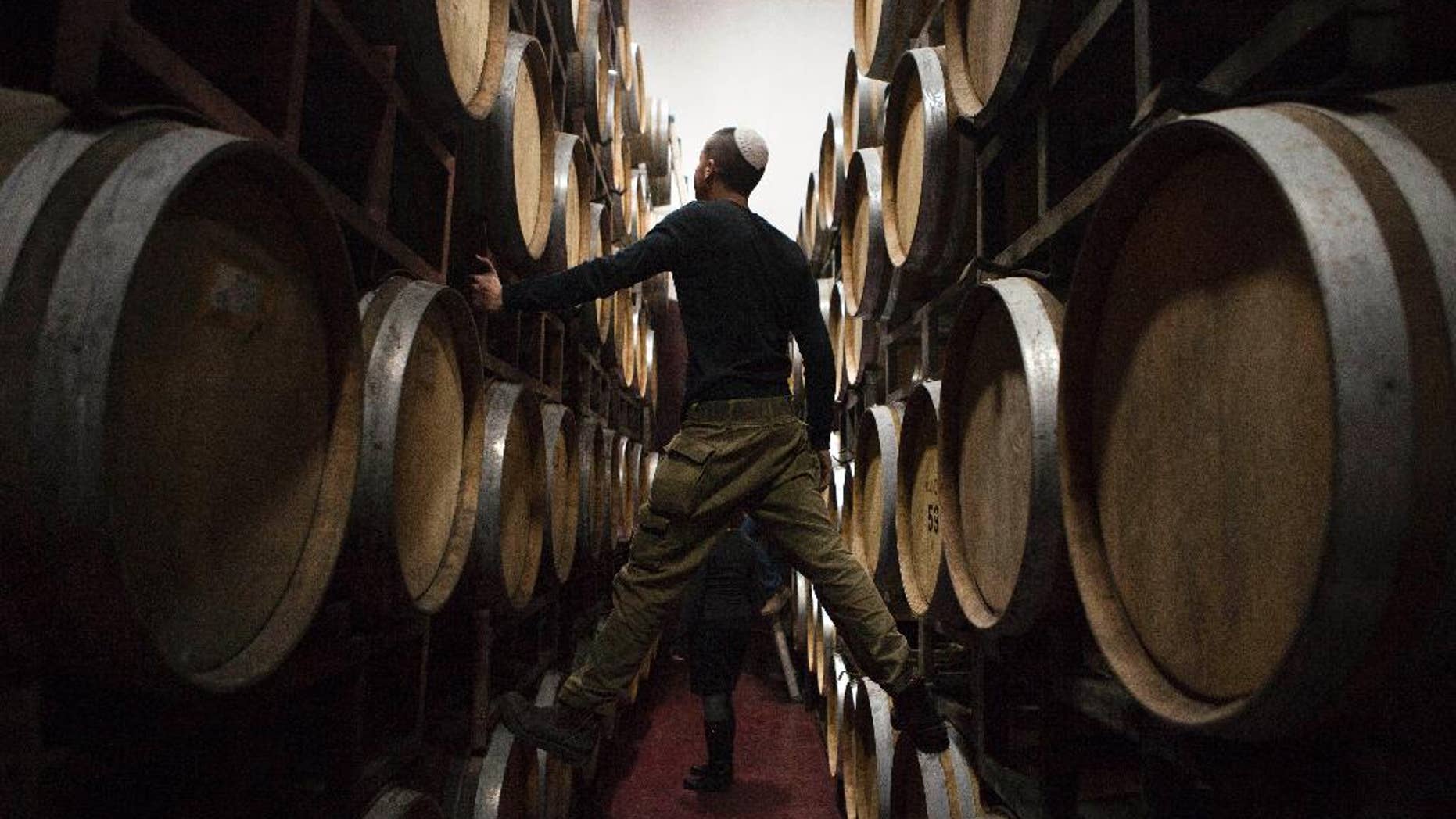FILE - In this Tuesday, Feb. 11, 2014 file photo, an Israeli worker inspects barrels in a winery in the West Bank settlement of Psagot. European Union officials said Tuesday, June 9, 2015, the the 28-nation bloc is preparing new guidelines that would require Israel to label products made in West Bank settlements if they are exported to Europe. (AP Photo/Dan Balilty, File)