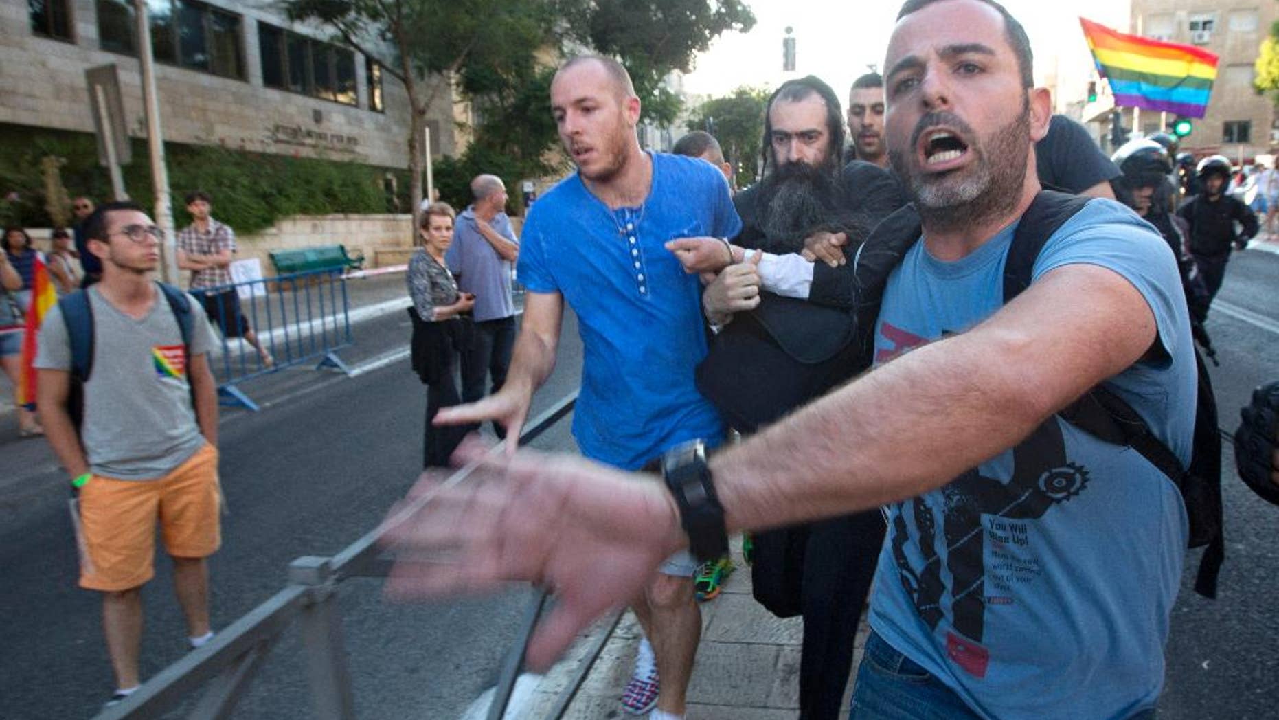 FILE - In this July 30, 2015 file photo, plainclothes Israeli police detain Yishai Schlissel, an ultra-Orthodox Jew, after he attacked people with a knife during a Gay Pride parade, in central Jerusalem. One of them, 16-year-old Shira Banki, later died of her wounds. Jerusalem's District Court indicted Schlissel for Banki's murder on Monday, Aug. 24, 2015, along with multiple attempted murder charges for those he wounded. Schlissel, who had been freed from prison weeks earlier after serving a sentence for stabbing several people at the city's pride parade in 2005. (AP Photo/Sebastian Scheiner, File)