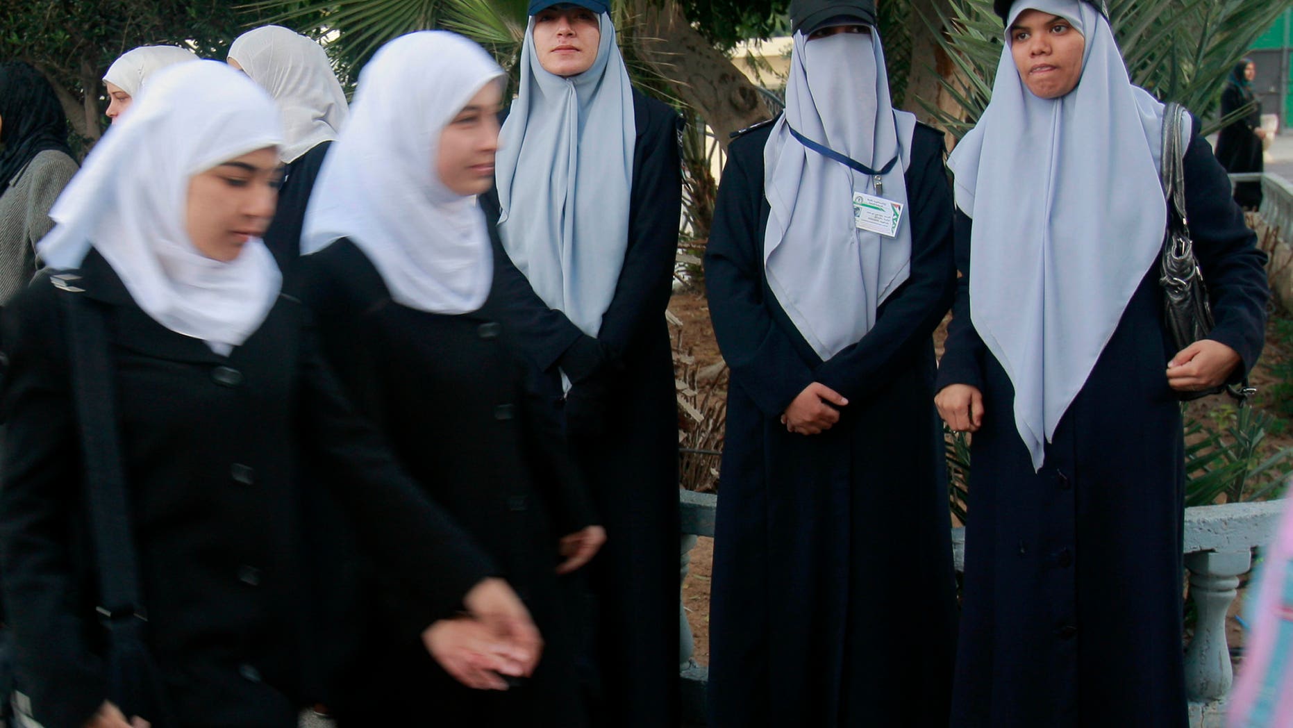 In this Dec. 9 photo, Palestinian school girls walk in front of Hamas female police officers in Gaza City. Gaza's ruling Hamas movement has embarked on a charm offensive in recent weeks.