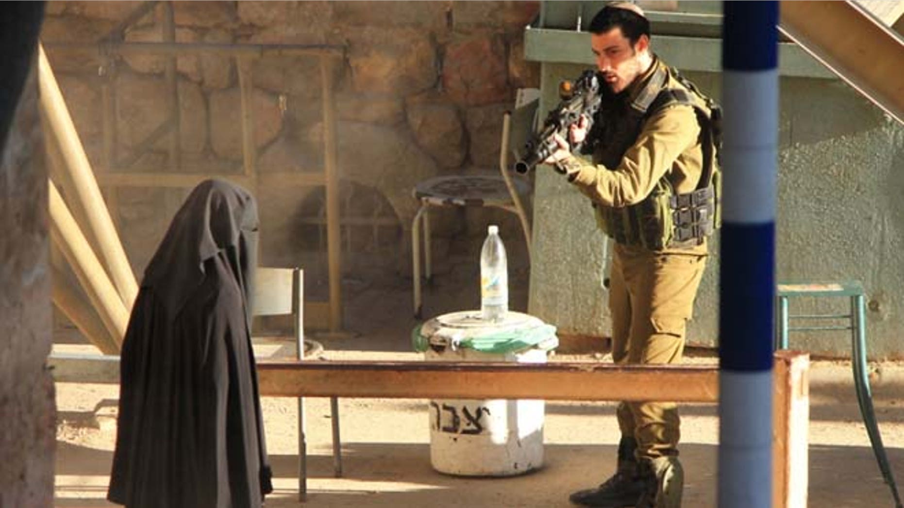 Sept. 22, 2015: An Israeli soldier aims at a Palestinian woman at a checkpoint in the West Bank city of Hebron.