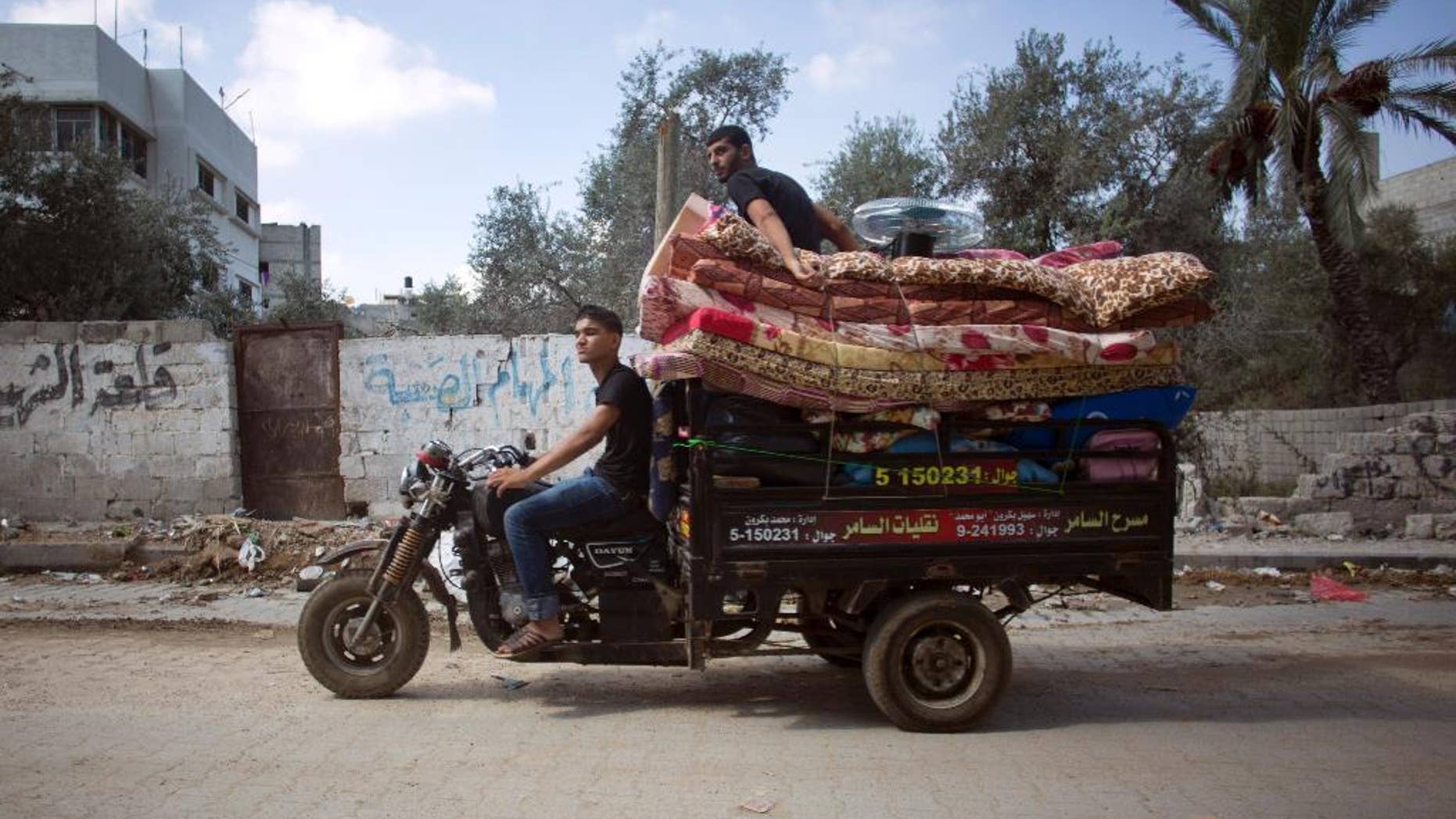 Palestinians with their belongings drive a motorbike back to their house in Gaza City's Shijaiyah neighborhood, Wednesday, Aug. 27, 2014. (AP Photo/Khalil Hamra)