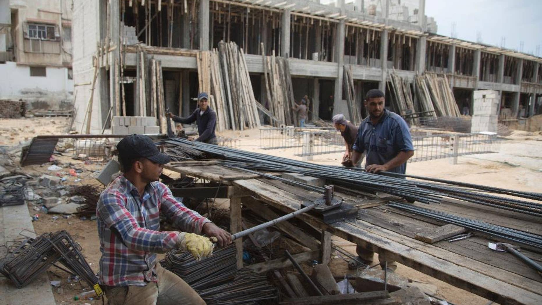 Palestinian construction laborers work on a U.N. school in the Gaza Strip, Saturday, Oct. 11, 2014. After the Gaza war, the U.N. brokered a deal with Israel and the Palestinian government under which Israel is to allow imports of construction materials for the private sector. On the Gaza side, the shipments are to be tracked by U.N. and Palestinian officials. (AP Photo/Khalil Hamra)