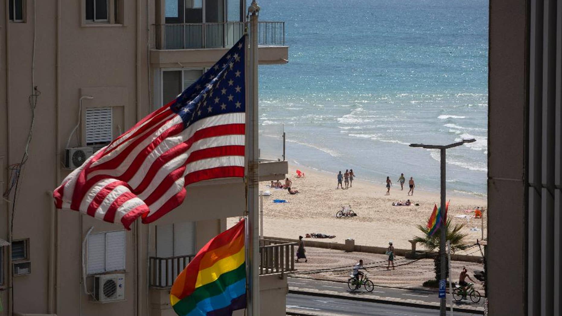 A U.S. flag is raised alongside a pride flag on the U.S. Embassy a day before the Gay Pride Parade in Tel Aviv, Israel, Thursday, June 12, 2014. In June, Tel Aviv celebrates its annual, week-long event that supports lesbian, gay, bisexual, transgender and their supporters, also known as the LGBT community. (AP Photo/Oded Balilty)