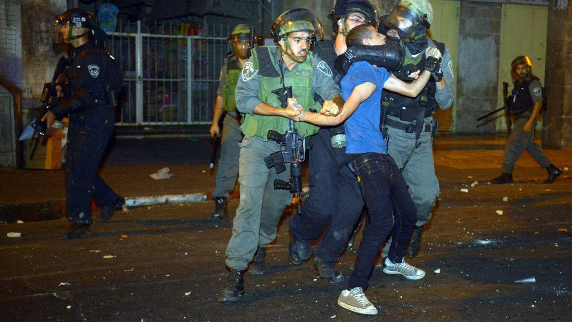 In this Monday, Sept. 8, 2014 photo Israeli border police officer detain a Palestinian teenager during clashes with Palestinian stone throwers that broke after the funeral of Mohammed Sunokrot in Jerusalem's Old City. While the world's attention was focused on the airstrikes and rockets over Gaza and Israel this summer, a wave of violence hit the streets of Jerusalem and is still roiling parts of this divided city at the core of the Israeli-Palestinian conflict. (AP Photo/Mahmoud Illean)