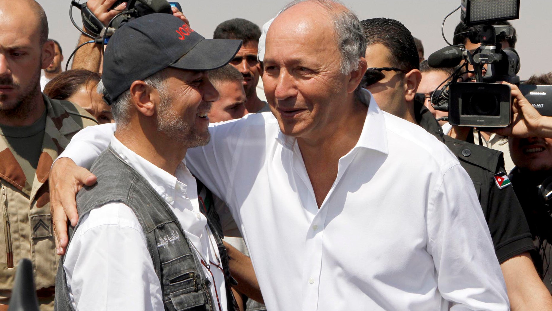 French Foreign Minister Laurent Fabius, right, greets an official from the Jordan Hashemite Charity Organization during his visit to the Zaatari Syrian refugee camp in Mafraq, Jordan, Thursday, Aug. 16, 2012. Fabius is on a three-day visit to countries neighboring Syria. (AP Photo/Raad Adayleh)