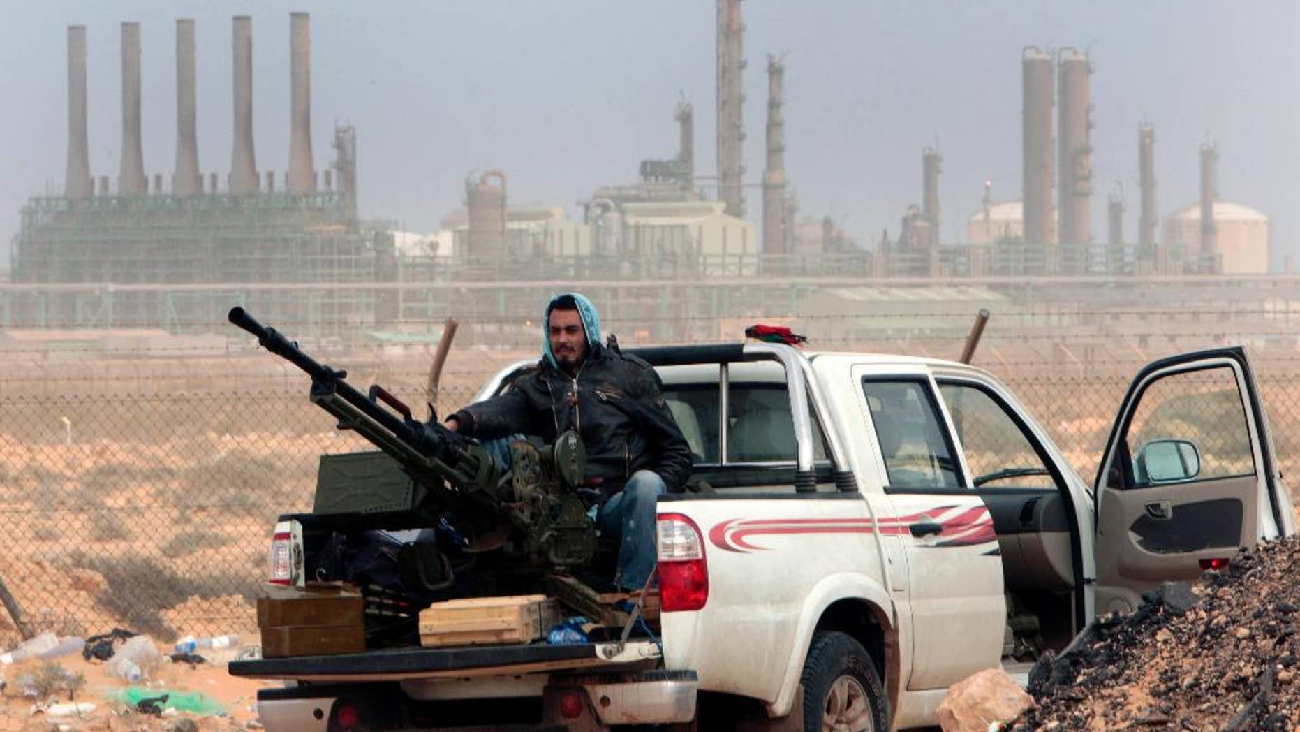 FILE - In this March 5, 2011 file photo, an anti-government rebel sits with an anti-aircraft weapon in front an oil refinery, after the capture of the oil town of Ras Lanouf, eastern Libya. The official Libyan news agency said Sunday, April 6, 2014 that the country's main militia in the east has agreed to hand back control of four oil terminals it captured and shut down last summer in its demand for a share in oil revenues. The shutdown has cost Libya millions of dollars. (AP Photo/Hussein Malla, File)