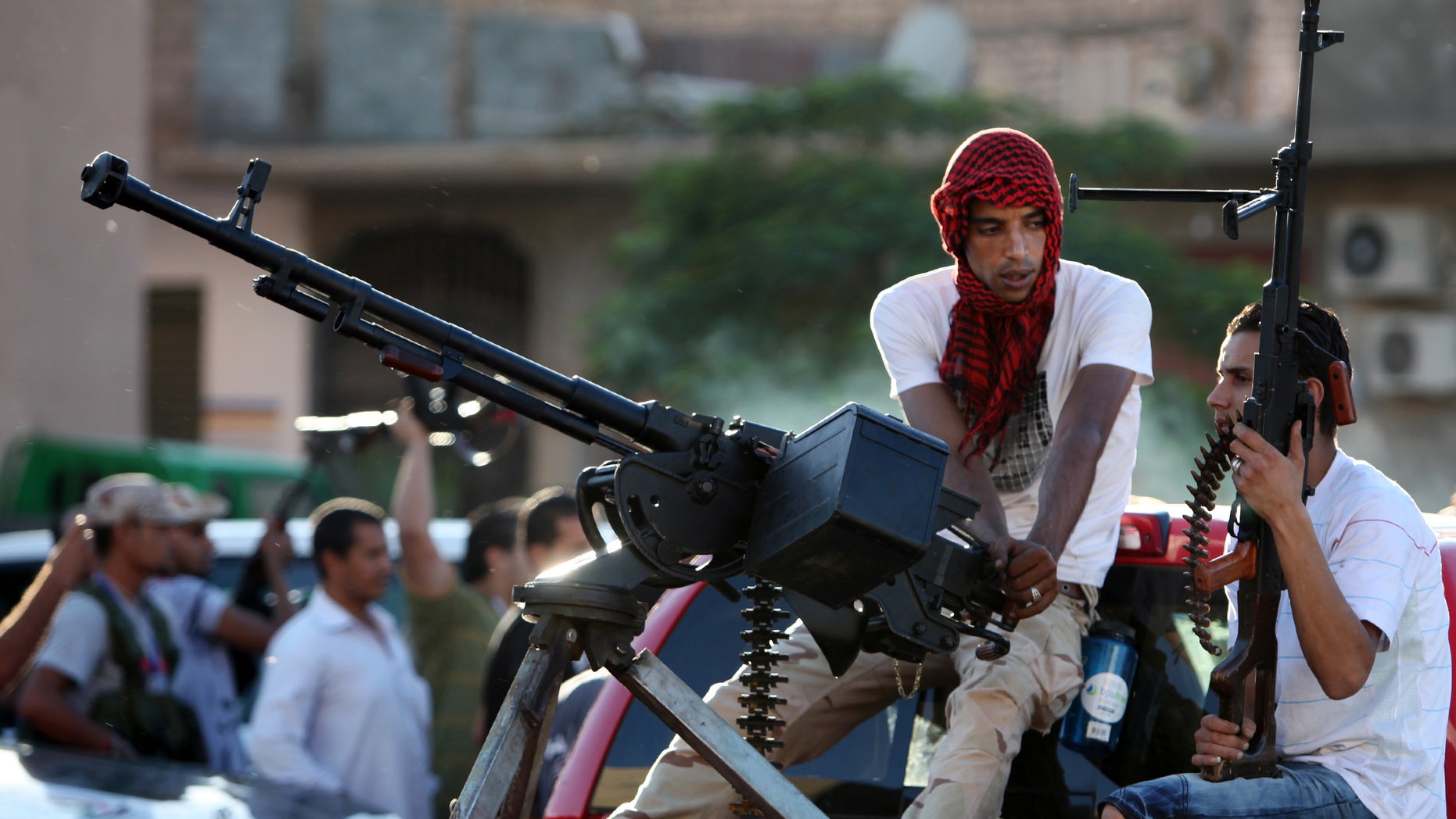 Revolutionary fighters sit on a truck mounted with a machine gun in the Abu Salim neighborhood of Tripoli, Libya, Friday, Oct. 14, 2011.