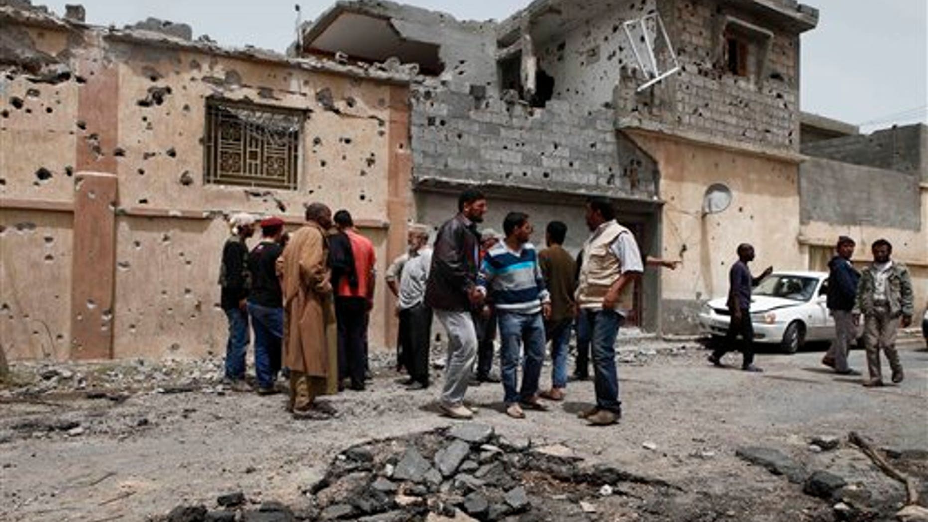 April 25: Neighbors examine the damage to a house which was struck by a shell in Misrata. Qaddafi's troops on the outskirts of Misrata unleashed more shells into the city Monday, hitting a residential area and killing 10 people, including five members of one family, according to a doctor in Misrata. (AP)