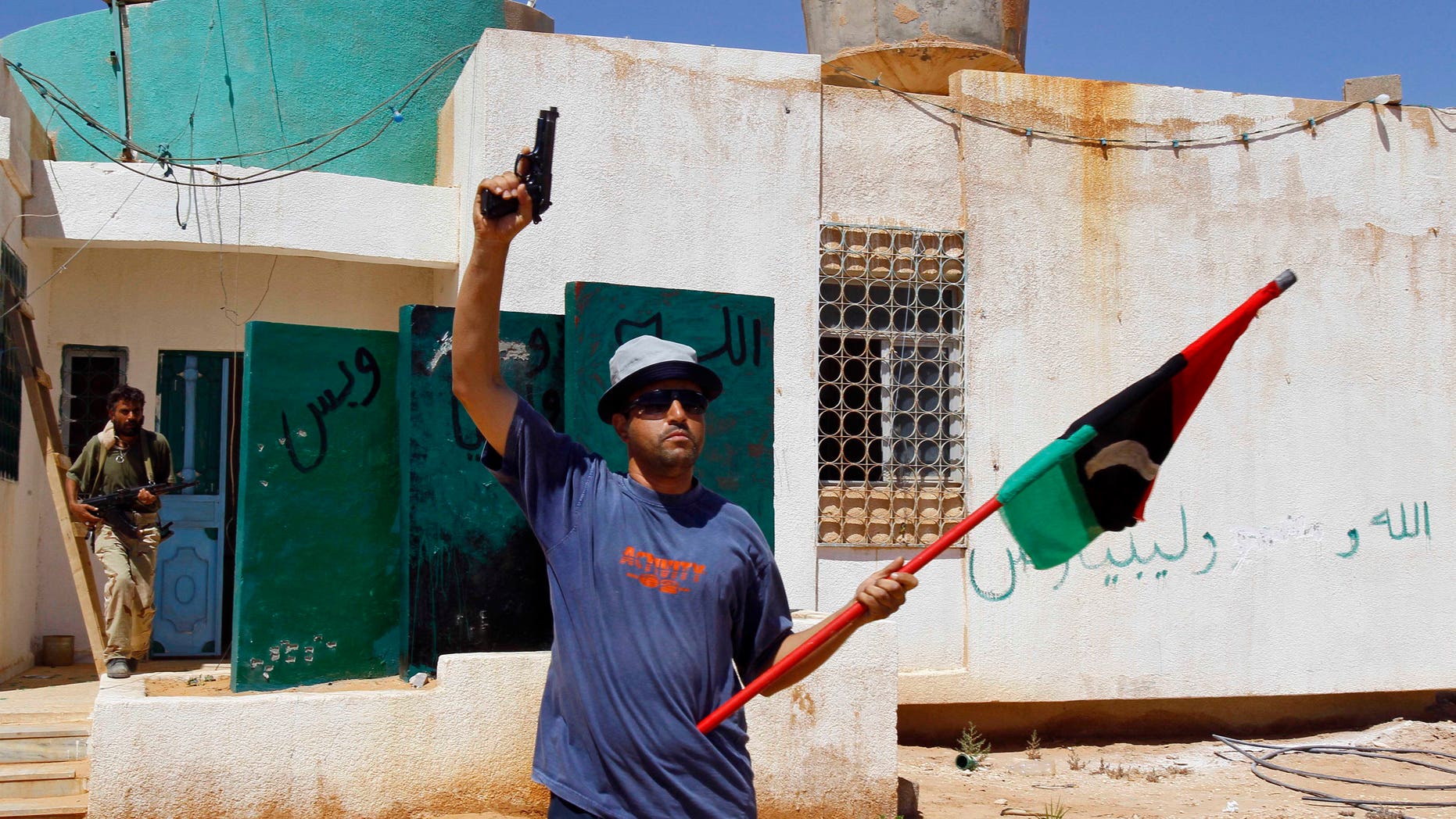 A Libya fighter celebrates as revolutionary fighters enter a Muammar Qaddafi political office next to a police station as they take control of Qaddafi loyalists villages in the desert some 730 km south of Tripoli, at Mahruga, 50 kms north of the southern city of Sebbah, Libya, Saturday, Sept. 17, 2011.