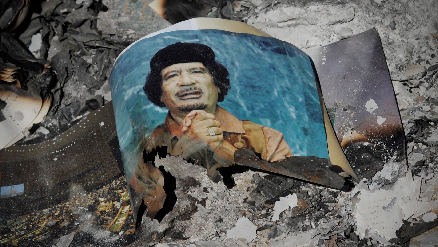 A picture of Libya's ousted leader Muammar Qaddafi is seen in the ashes in downtown Sirte, Libya, Wednesday, Oct. 12, 2011.
