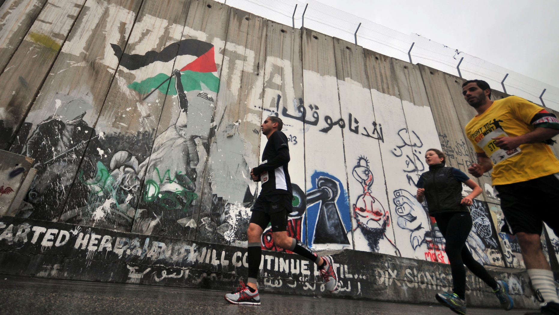 April 21, 2013: People run past the separation wall during the West Banks first marathon in Bethlehem. About 1,000 people participated in the race, which included shorter 10-kilometer and 20-kilometer options.