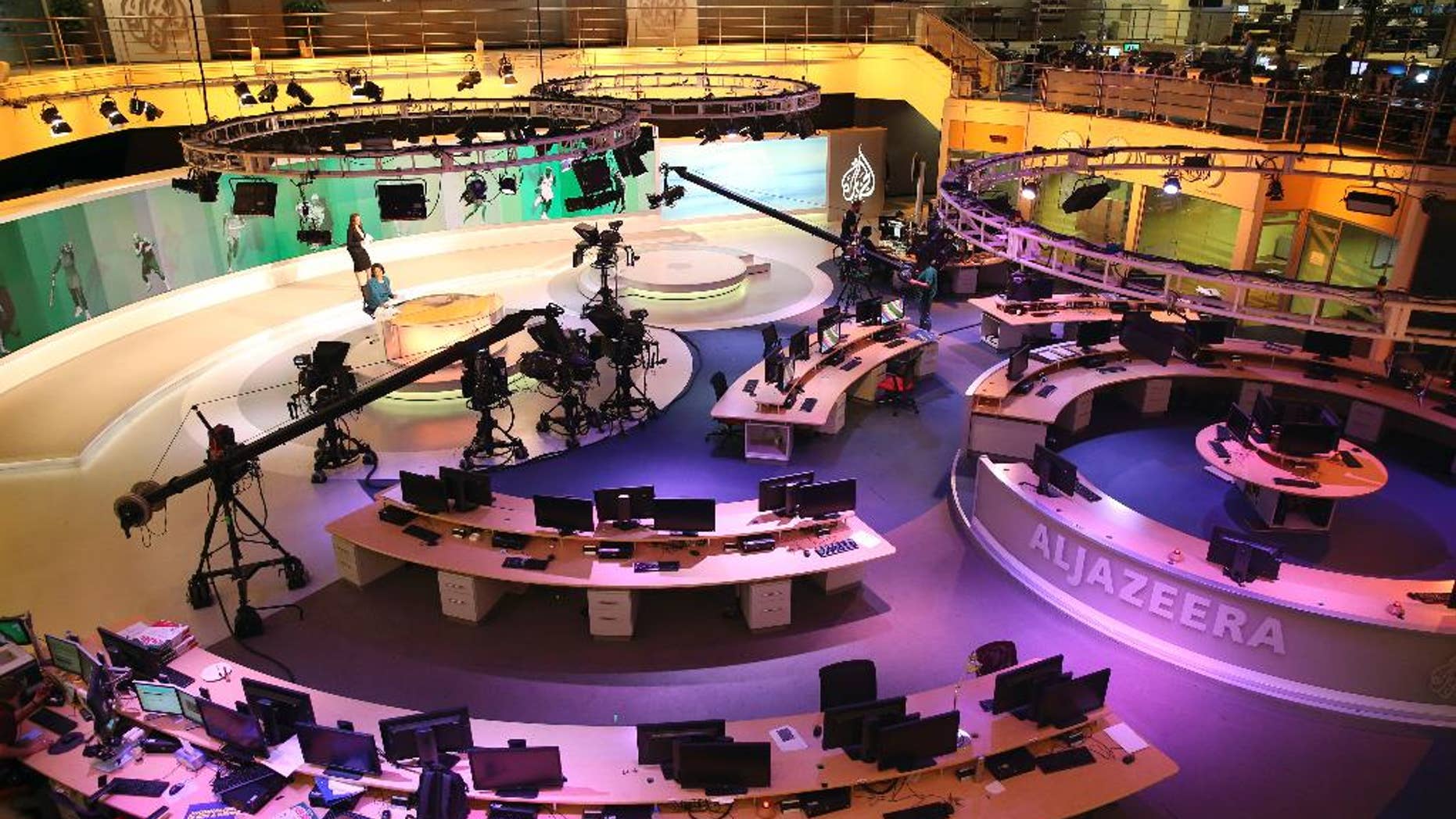 FILE- In this Jan. 1, 2015, file photo, staff members of Al-Jazeera International work at the news studio in Doha, Qatar. Ahmed Mansour, a prominent Al-Jazeera Arabic journalist, was detained Saturday, June 20, in Germany over an Egyptian arrest warrant, the Qatar-based broadcaster reported. (AP Photo/Osama Faisal, File)