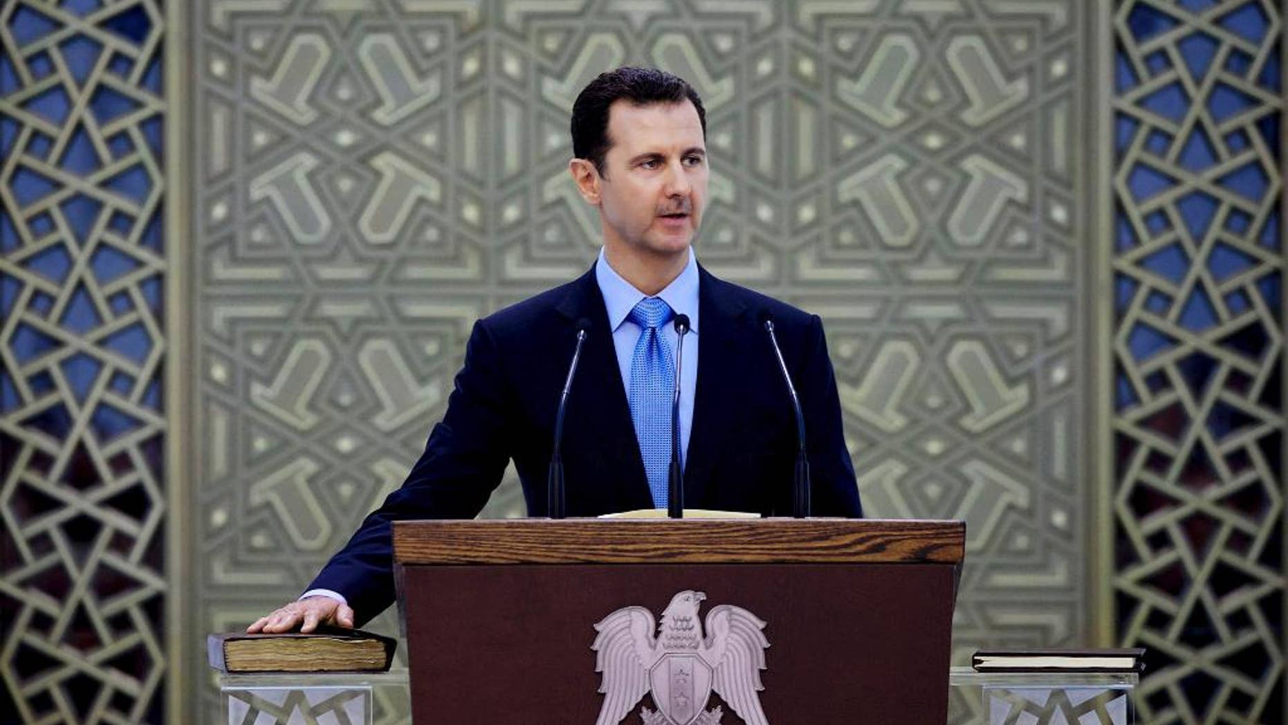 FILE - In this Wednesday, July 16, 2014 file photo released by the Syrian official news agency SANA, Syria's President Bashar Assad is sworn for his third, seven-year term, in Damascus, Syria. Assad said in remarks published Wednesday that U.S.-led airstrikes targeting Islamic State group militants in his country are neither serious nor efficient, claiming they have failed to produce any tangible results. (AP Photo/SANA, File)