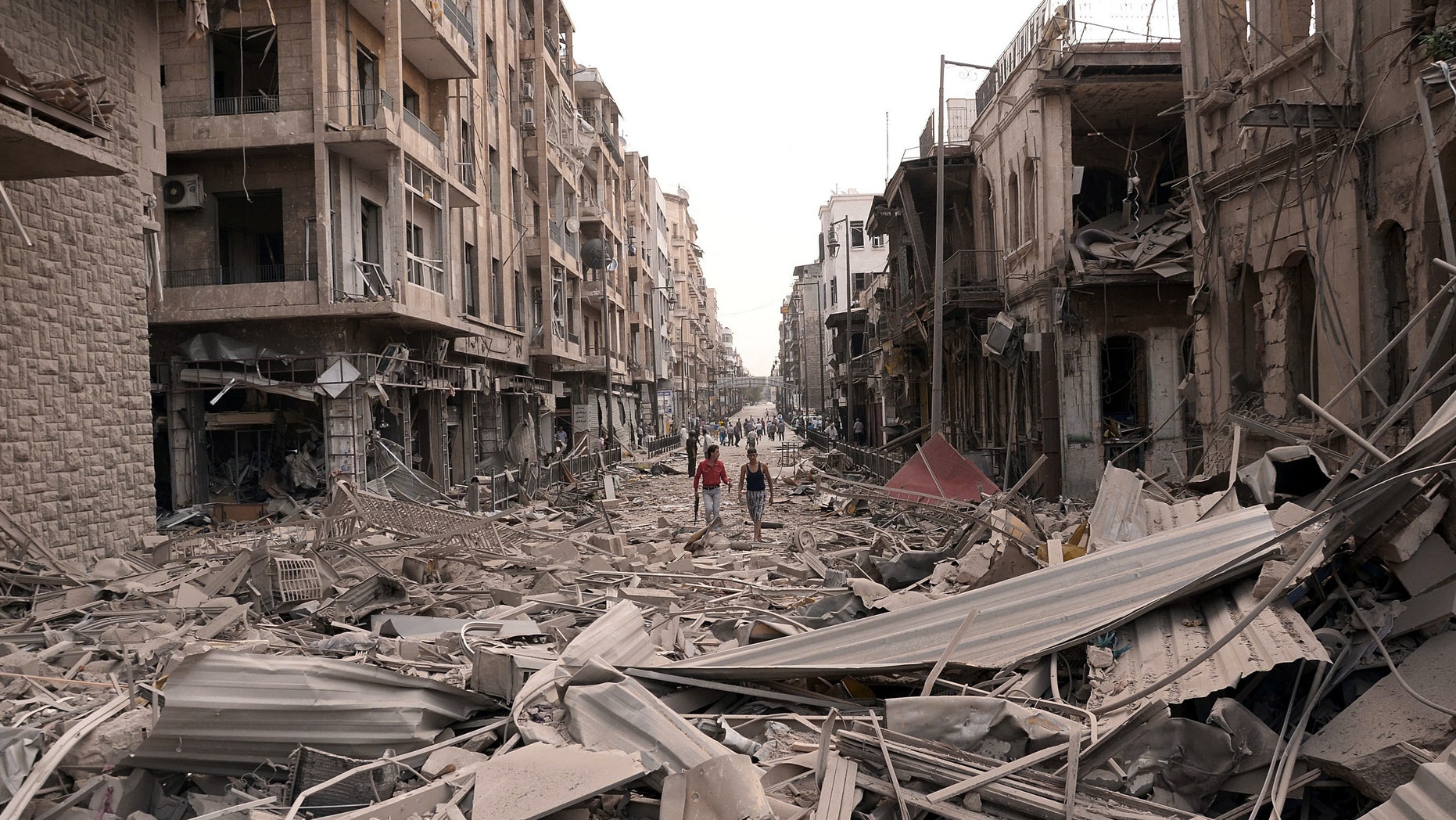 FILE - In this Wednesday, Oct. 3, 2012 file photo released by the Syrian official news agency SANA, Syrian men walk at a street between destroyed buildings where triple bombs rocked at the Saadallah al-Jabri square, in Aleppo city, Syria. Nearly 19 months of violence in Syria have left their mark everywhere: Entire blocks of apartment buildings have been shattered, their top floors reduced to pancaked concrete. Centuries-old markets have been gutted billions of dollars along with an irreplaceable chunk of history wiped out in just few hours of battle. Oil pipelines, factories, schools, hospitals and churches and mosques have been systematically destroyed. (AP Photo/SANA, File)