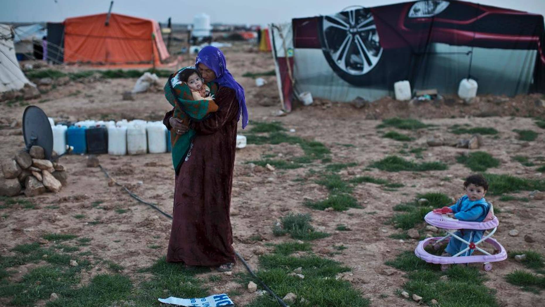 FILE - In this Sunday, March 8, 2015 file photo, Syrian refugee Rifaa Ahmad, 50, cuddles her granddaughter at an informal tented settlement near the Syrian border, on the outskirts of Mafraq, Jordan. Kuwait opened an international donors’ conference for Syria on Tuesday, March 31, 2015 with a pledge of $500 million in humanitarian aid as the United Nations issued its largest yet appeal for $8.4 billion in commitments this year for the war-ravaged country.(AP Photo/Muhammed Muheisen, File)