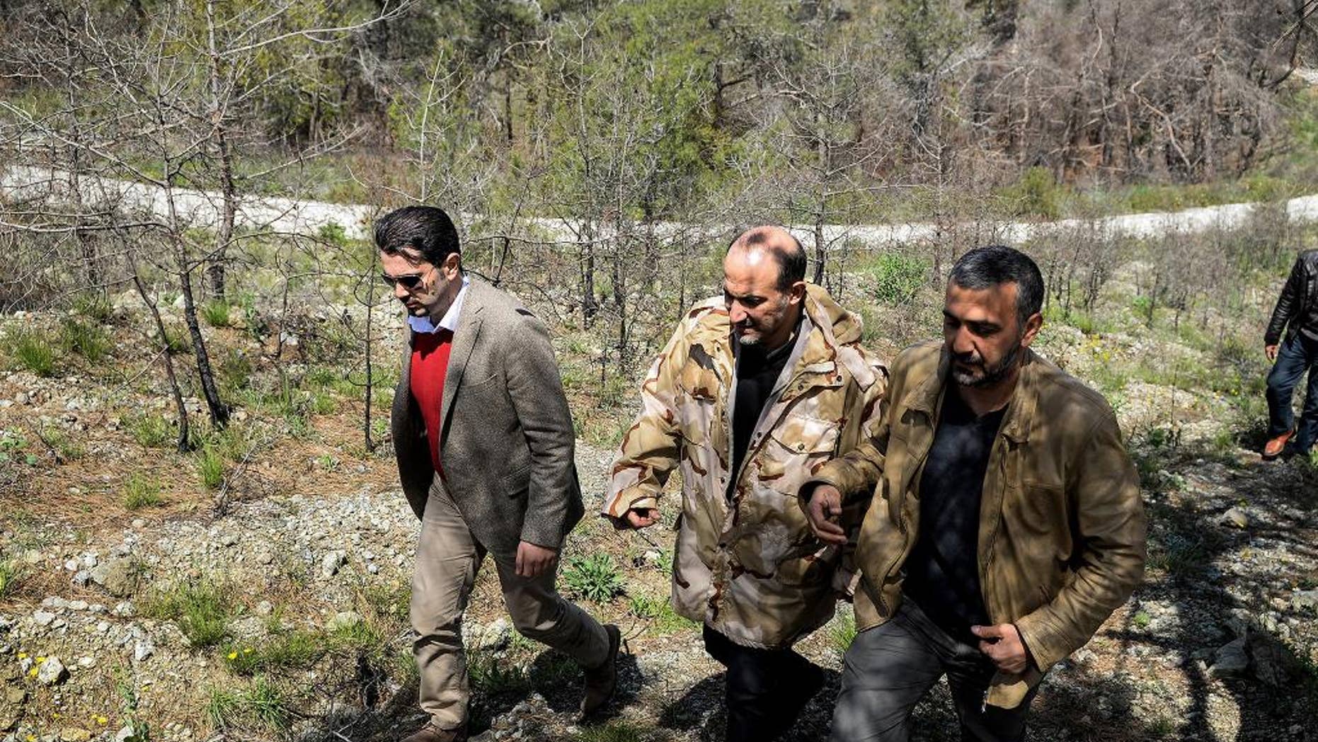 In this picture released by the Syrian National Coalition Media Office, Ahmad al-Jarba, center, the head of the delegation of the Syrian National Coalition, who wears a camouflage jacket during his rare visit to the front lines where the rebels fighting against the Syrian government troops, in the coastal province of Latakia, Syria, Tuesday April 1, 2014. Al-Jarba visited Kassab during his trip to the Latakia’s front lines, the Western-backed Syrian National Coalition said in a statement. (AP Photo / The Syrian National Coalition Media Office)