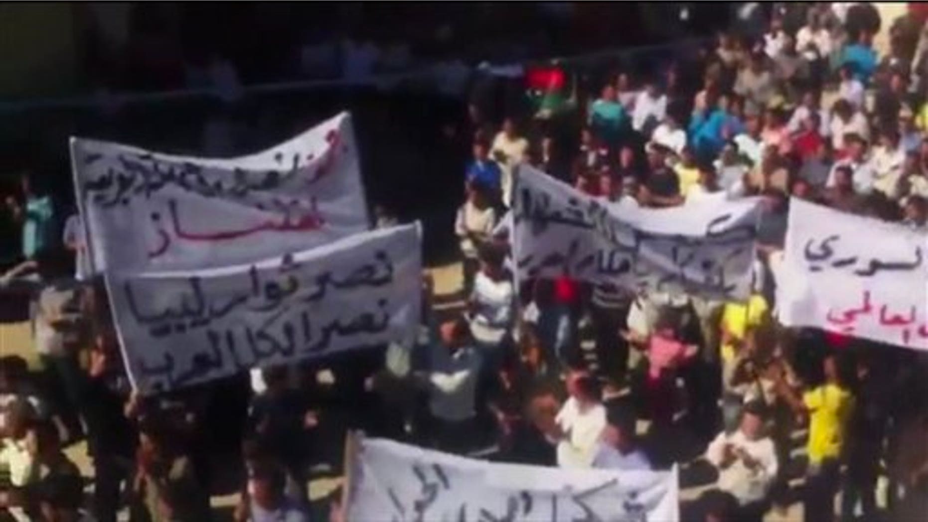 In this image made from amateur video released by Ugarit News and accessed via The Associated Press Television News, a banner at left, in Arabic, reads, "the victory of the Libyan rebels is a victory for all Arabs" in Idlib, Syria.