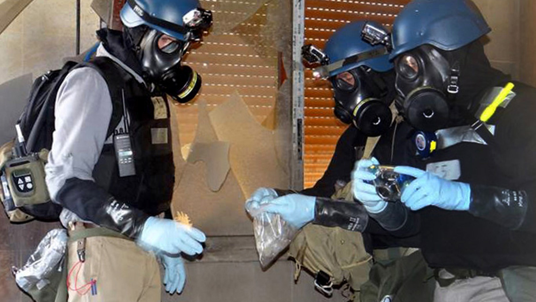 Aug. 29, 2013: In this file citizen journalism image provided by the Local Committee of Arbeen which has been authenticated based on its contents and other AP reporting, members of the UN investigation team take samples from the ground in the Damascus countryside of Zamalka, Syria.