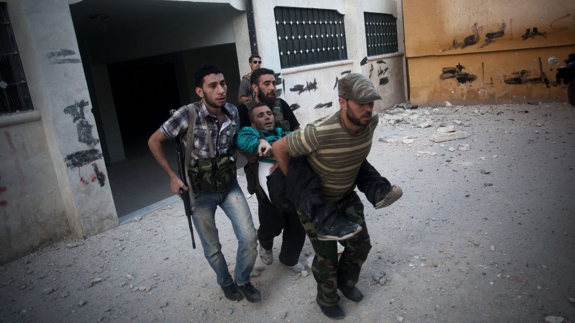 In this Saturday, Sept 8, 2012 photo, Free Syrian Army soldiers help a severely wounded fighter after he was shot by a Syrian Army sniper in the Izaa district of Aleppo, Syria. Syrian activists say President Bashar Assad's regime pounded Aleppo with warplanes and artillery shelling Saturday as ground forces seeking to regain momentum in the country's largest city advanced on three neighborhoods. (AP Photo/Manu Brabo)