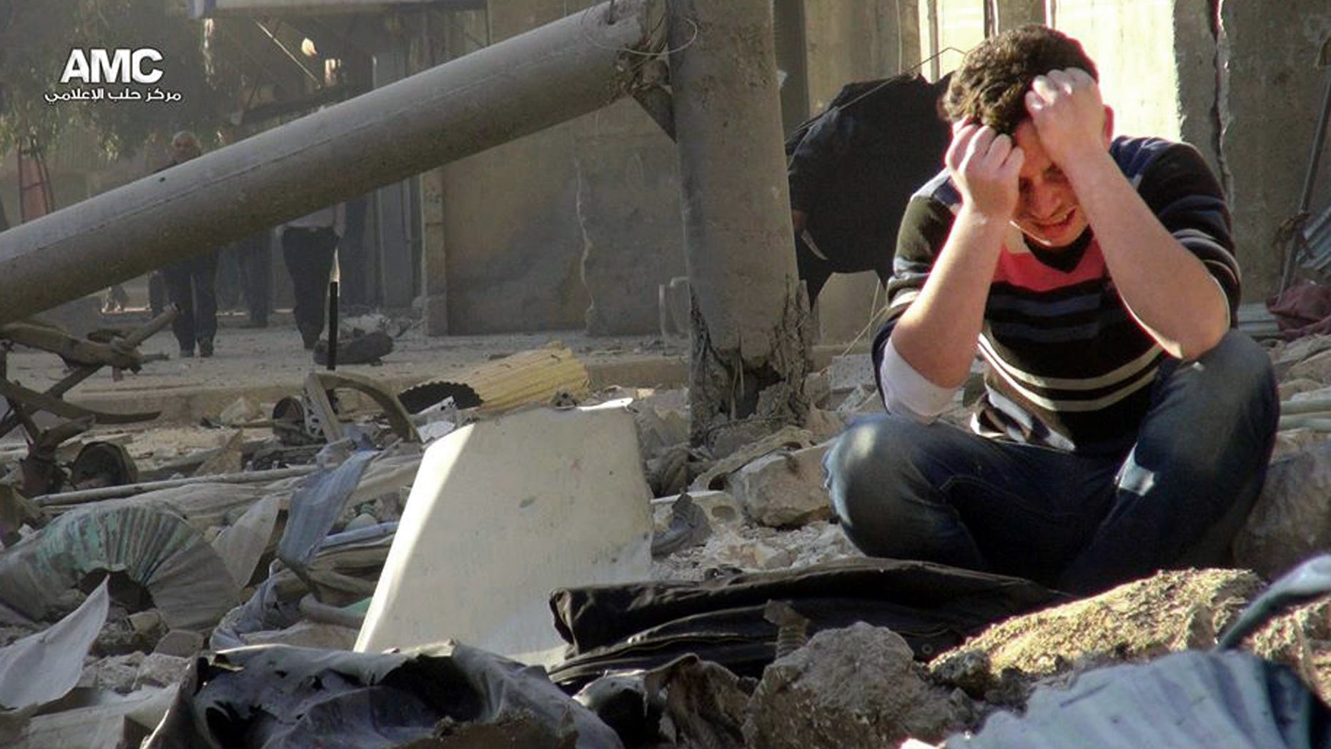 In this Monday, Dec. 23, 2013 citizen journalism image provided by Aleppo Media Center AMC, which has been authenticated based on its contents and other AP reporting, A Syrian man mourns as he sits in the rubble of buildings following a Syrian government airstrike in Aleppo, Syria. Government forces widened a bombing campaign in rebel-held areas of northern Syria on Monday, striking the northern city of Aleppo and a town on the Turkish border in raids that left an estimated 45 people dead, activists said. (AP Photo/Aleppo Media Center AMC)