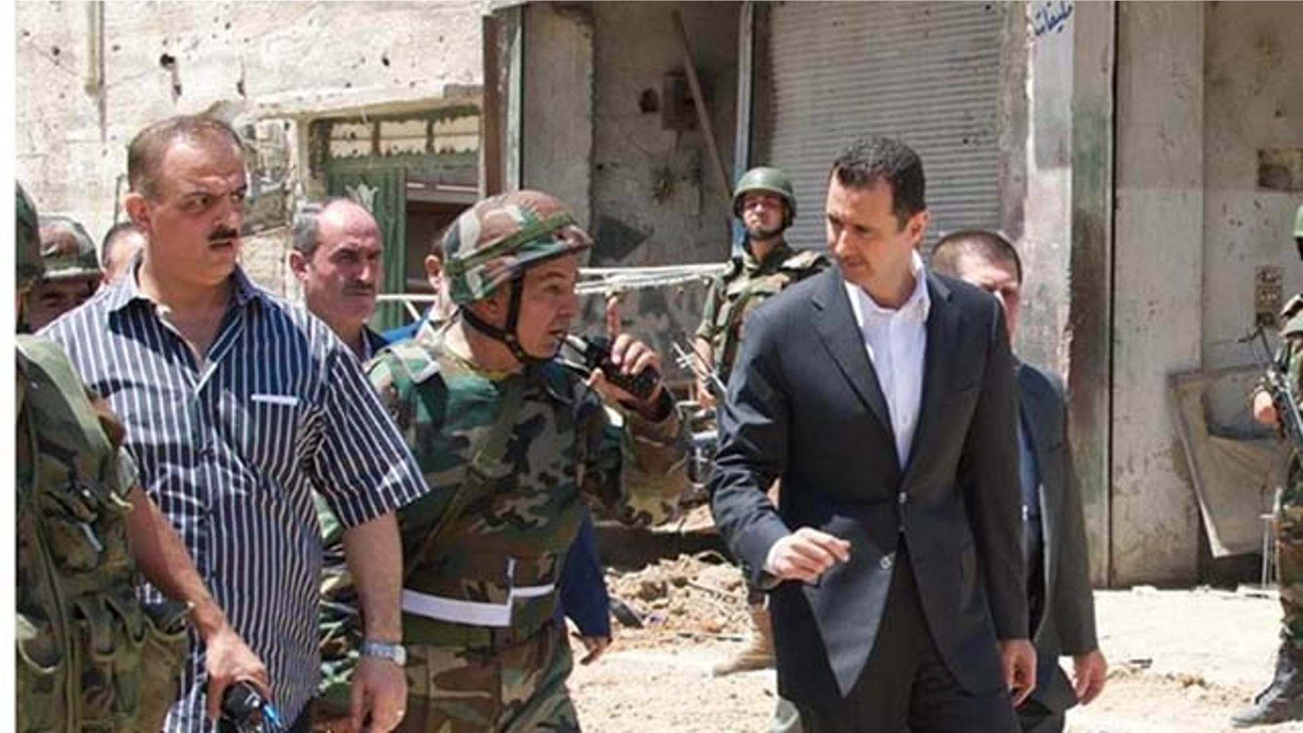August 1, 2013: This image posted on the official Facebook page of the Syrian Presidency purports to show Syrian President Bashar Assad walking with soldiers with during Syrian Arab Army day in Darya, Syria (AP Photo)