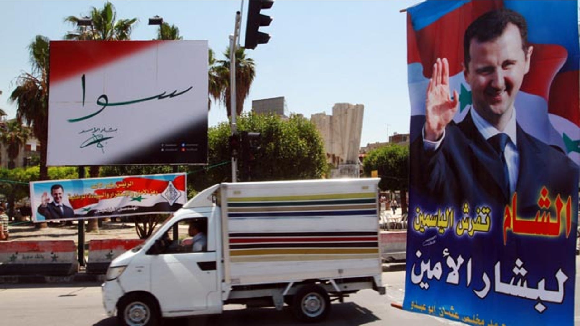 May 12, 2014: A vehicle drives past campaign posters for the June 3 presidential election in Damascus, Syria. (AP Photo)