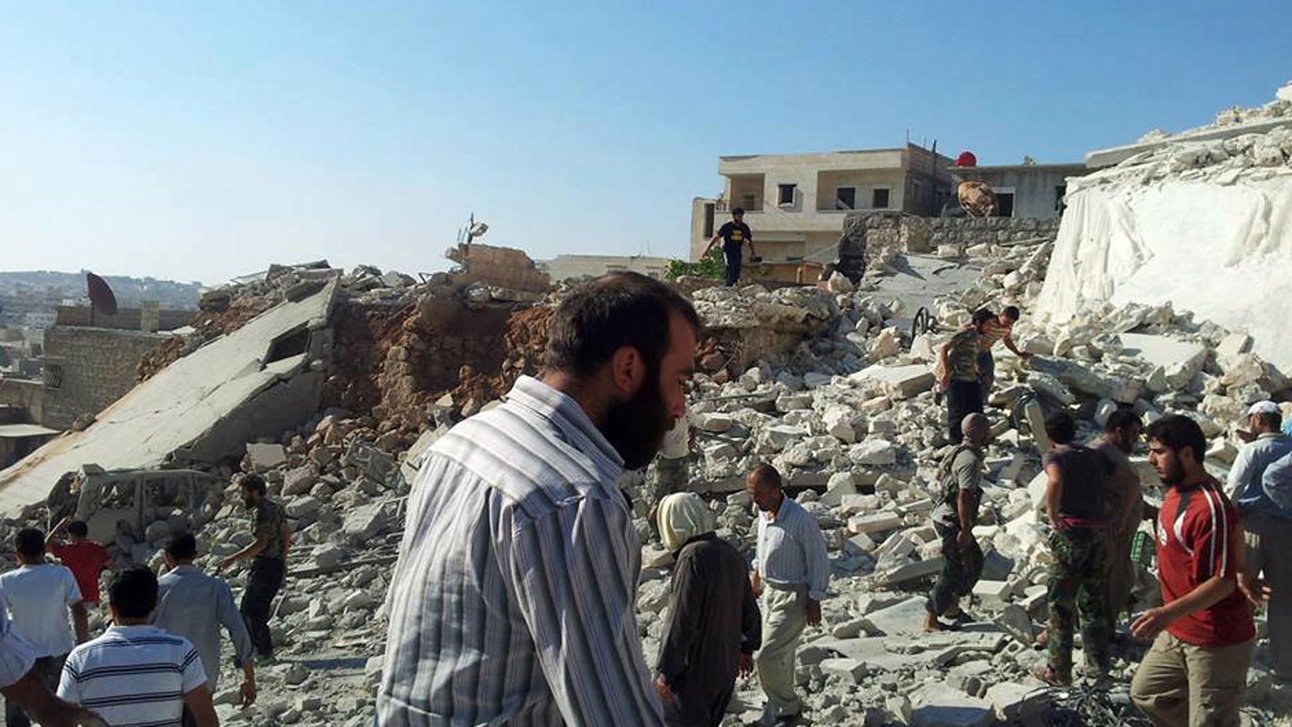 Syrian citizens standing on rubble of destroyed houses that were damaged by Syrian forces airstrike in Aleppo.