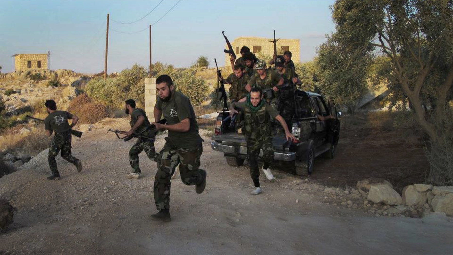 In this citizen journalism image taken on Friday, July 13, 2012 and provided by Edlib News Network ENN, Free Syrian Army soldiers run for cover in Idlib province, northern Syria. (AP Photo/Edlib News Network ENN) THE ASSOCIATED PRESS IS UNABLE TO INDEPENDENTLY VERIFY THE AUTHENTICITY, CONTENT, LOCATION OR DATE OF THIS HANDOUT PHOTO