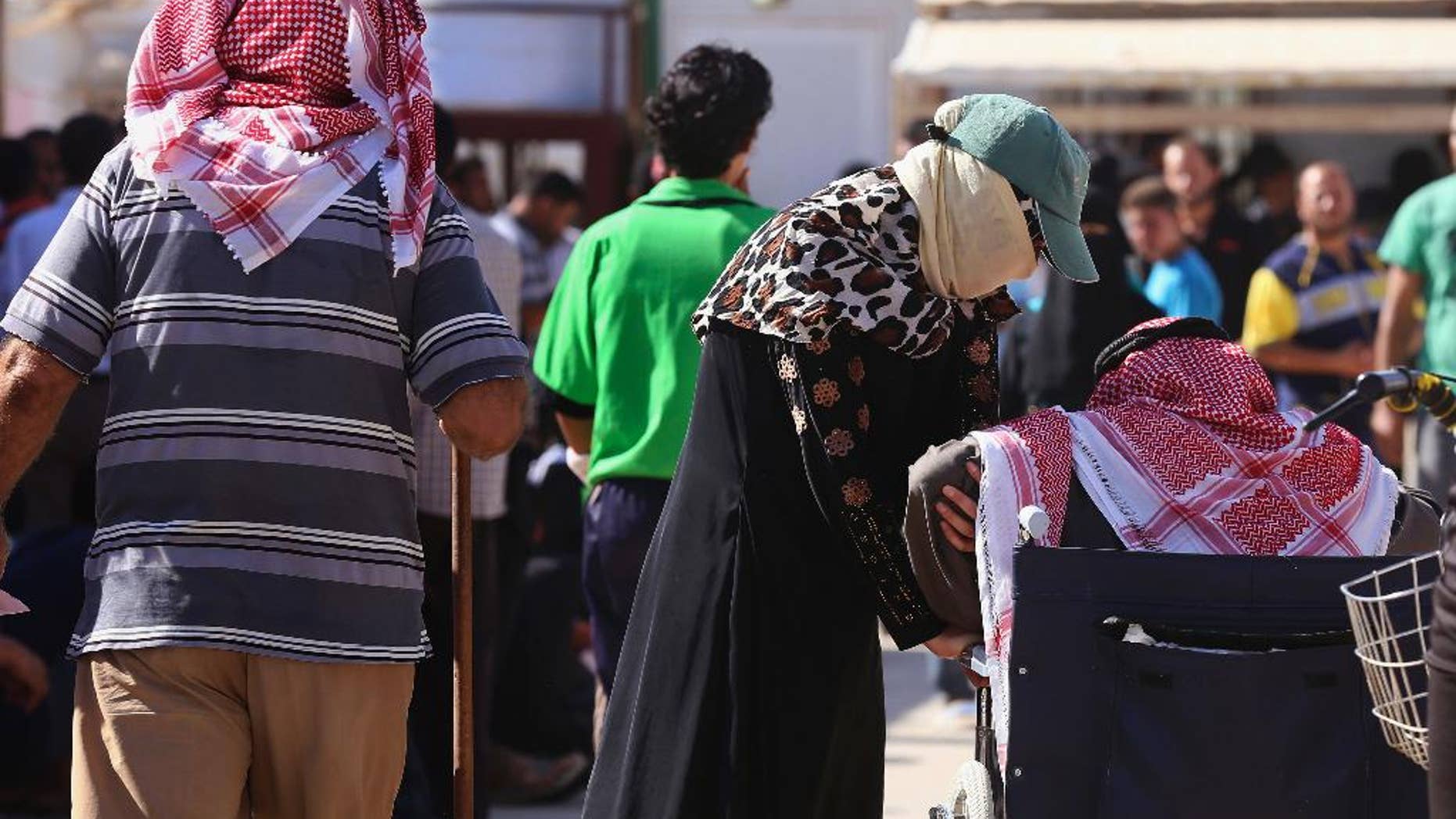 In this Thursday, Oct. 1, 2015 photo, Syrian refugees wait to sign up for a return bus to the Syrian border, at the U.N.-run Zaatari refugee camp near Mafraq, northern Jordan. Growing numbers of Syrian refugees are returning to their war-ravaged homeland from Jordan because they can't survive in exile after drastic aid cuts, can't afford to pay smugglers to sneak them into Europe or are simply homesick. (AP Photo/Raad Adayleh)