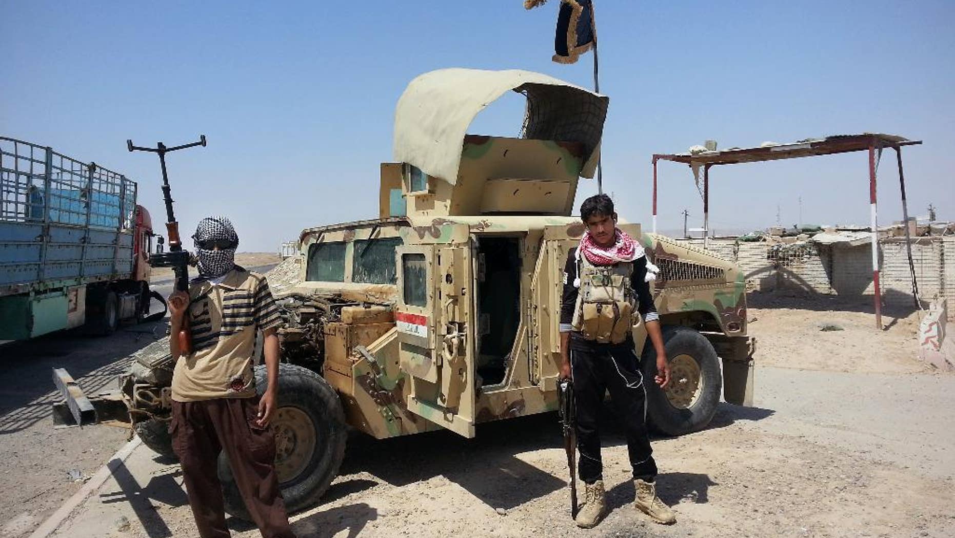 FILE - In this Thursday, June 19, 2014 file photo, Islamic State group militants stand with a captured Iraqi Army Humvee at a checkpoint outside Beiji refinery, some 250 kilometers (155 miles) north of Baghdad, Iraq. The Syrian foreign ministry said Tuesday, Sept. 23, 2014 that Washington informed Damascus' envoy to the United Nations before launching airstrikes against the Islamic State group in Syria, attacks that activists said inflicted casualties among jihadi fighters and civilians on the ground.(AP Photo)