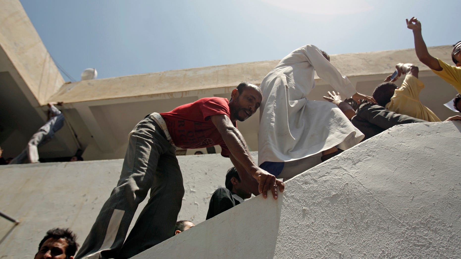 Students climb as they protest at the Sanaa University campus to show their support for a boycott of university studies as part of protests demanding the resignation of Yemeni President Ali Abdullah Saleh, in Sanaa,Yemen, Saturday, Sept. 17, 2011.