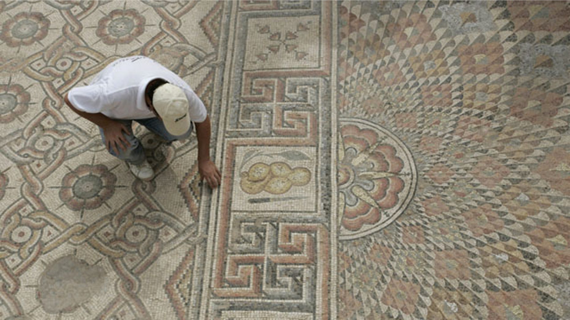 An unidentified man examines part of a mosaic, measureing around 9,700 square feet (900 square meters), in ruins of an 8th-century Islamic palace outside the West bank town of Jericho, Sunday, Oct. 10, 2010.