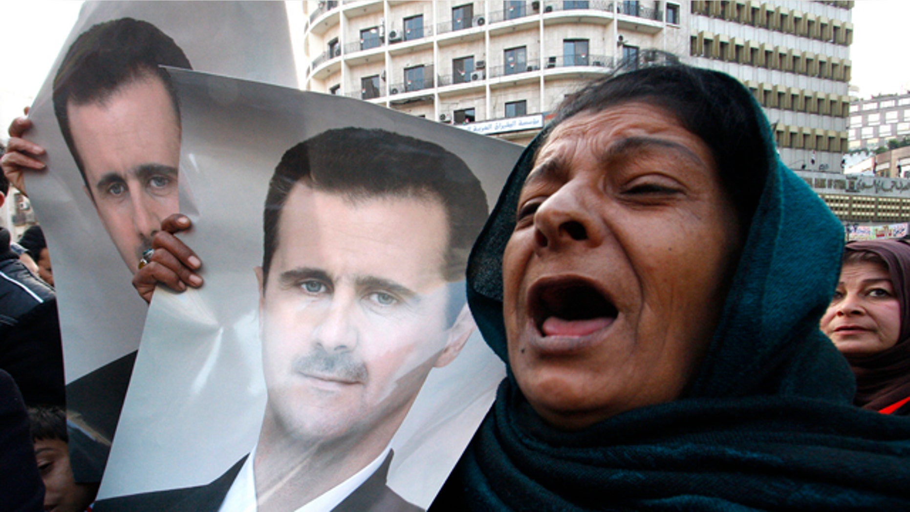 Wed. Jan 25, 2012: Pro-Syrian regime protesters, shout slogans and holds portrait of Syrian President Bashar Assad during a demonstration to show their solidarity for their president, in Damascus, Syria. Government forces clashed with army defectors and stormed rebellious districts in central Syria on Wednesday, firing mortars and deploying snipers in violence that killed at least seven people, including a mother and her 5-year-old child, activists said. (AP Photo)