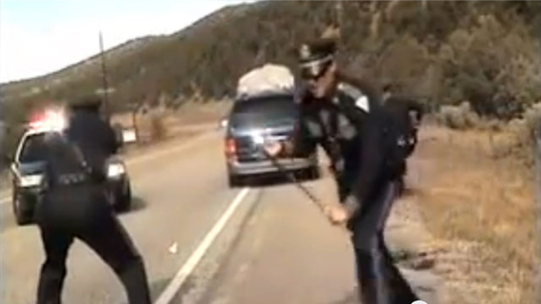 October 28, 2013: Three New Mexico State Police officers react as a minivan driven by motorist Oriana Farrell pulls away from a chaotic traffic stop that included one officer bashing the van's window with his night stick and another, Elias Montoya, at left, firing three shots as the van drives off, in this video made from the dashboard camera of the police cruiser. Montoya, the officer who fired at the van full of children, has been suspended. (AP Photo/New Mexico State Police)