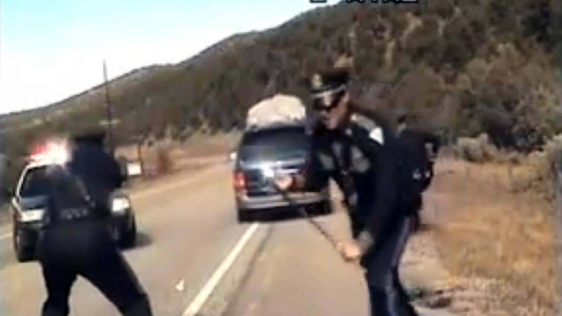 FILE - This file image from video provided by the New Mexico State Police shows three New Mexico State Police officers reacting as a minivan driven by motorist Oriana Farrell pulls away from a traffic stop on Oct. 28, 2013. New Mexico prosecutors aim to file new charges against Farrell in the chaotic traffic stop and chase last year during which a New Mexico State Police officer fired shots at her minivan full of children. The New Mexico Court of Appeals recently tossed Farrell's charges, including fleeing an officer and child abuse. (AP Photo/New Mexico State Police, File)