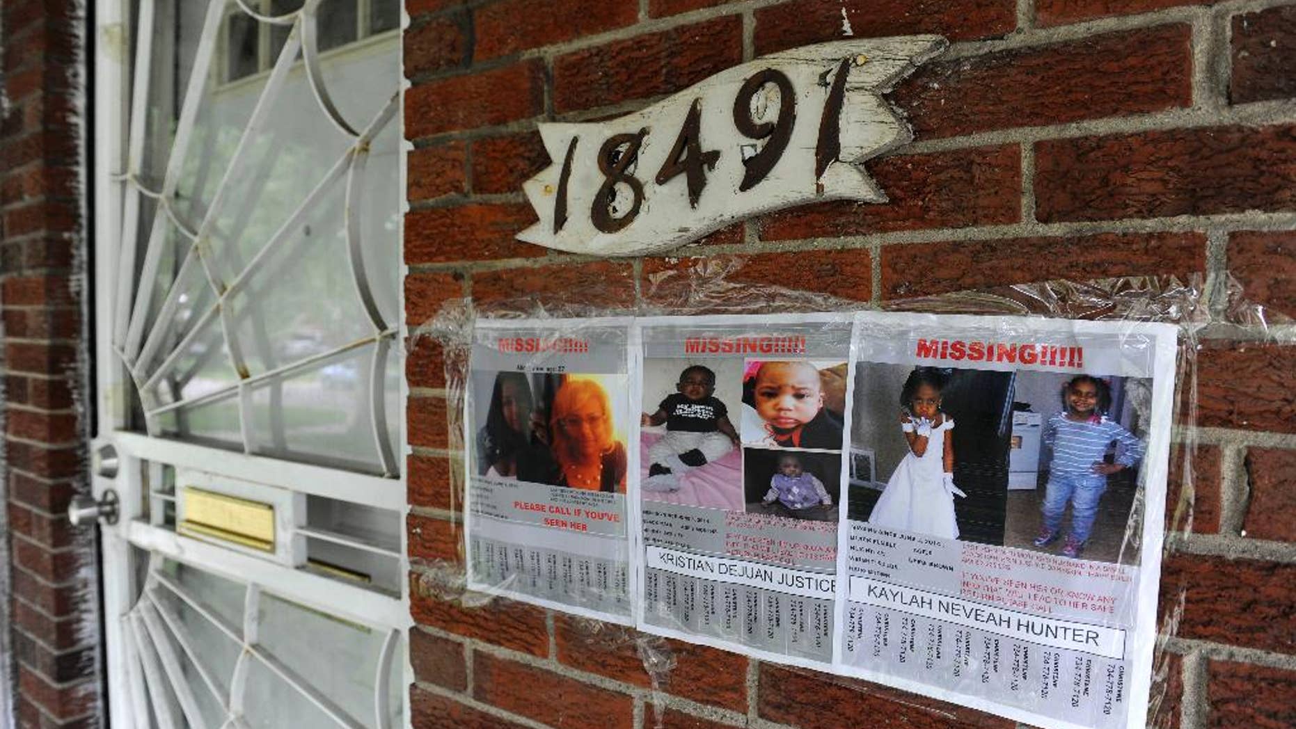 Flyers of a missing woman and children are taped to the brick home of Alicia Fox, Tuesday, June 10, 2014, in Detroit. Police and the FBI are searching for two young Detroit siblings, 6-year-old Kaylah Hunter and 6-month-old brother, Kristian Justice, after their 27-year-old mother was found shot to death in a vacant house about six miles from her home. No suspects have been identified. (AP Photo/Detroit News, David Coates) DETROIT FREE PRESS OUT; HUFFINGTON POST OUT.
