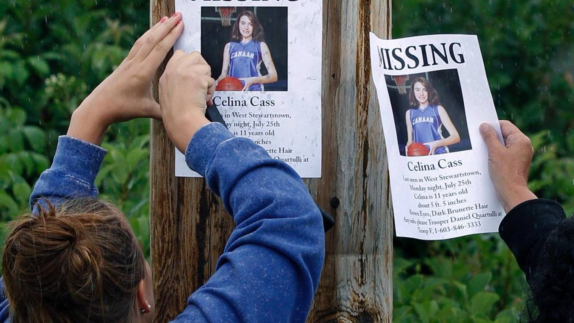FILE - In this July 28, 2011 file photo, Kaylin Pettit, of Stewartstown, N.H., left, and Lori McKearney, of Lancaster, N.H. tack missing posters for Celina Cass to a utility pole in Colebrook, N.H. A week after Cass went missing from her family's West Stewartstown apartment on July 25, 2011, her body was found near a dam in the Connecticut River. Four years later, no one has been charged with her death, which investigators have called a homicide. (AP Photo/Charles Krupa, File)