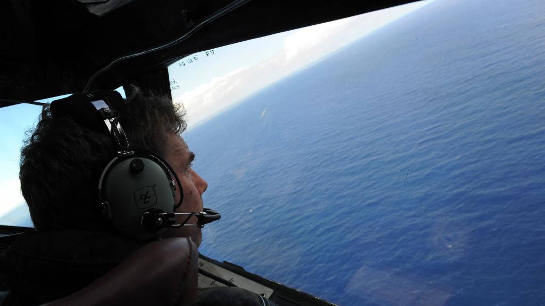FILE - In this April 13, 2014, file photo taken from the Royal New Zealand air force (RNZAF) P-3K2-Orion aircraft, co-pilot Squadron Leader Brett McKenzie looks out of a window while searching for debris from missing Malaysia Airlines Flight 370, in the Indian Ocean off the coast of western Australia. Even with the recent discovery of a possible wing fragment from the missing airplane on Wednesday, July 29, 2015, on a remote island in the Indian Ocean, tracing the route of the debris back across Indian Ocean may prove impossible. (Greg Wood/Pool Photo via AP)