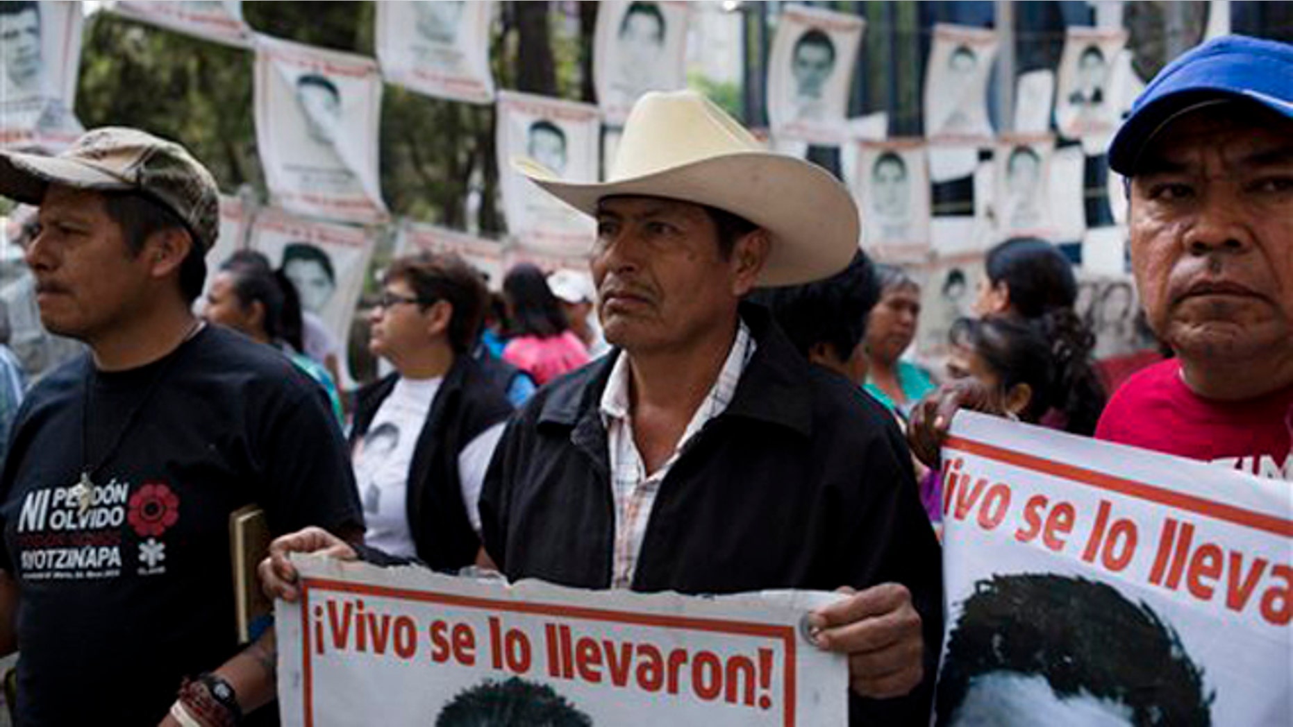 Relatives of 43 missing students from the Isidro Burgos rural teachers' college hold pictures of their missing loved ones after meeting with Attorney General Arely Gomez Gonzalez in Mexico City, Thursday, March 17, 2016. His sign reads in Spanish: "They took them alive!." In September of 2014, several students and bystanders were killed and 43 students vanished in the city of Iguala, allegedly taken by police and then handed over to a criminal gang who burned their bodies in a garbage dump, according to a federal investigation. Families of the missing and independent investigators cast doubts on the official version. (AP Photo/Eduardo Verdugo)