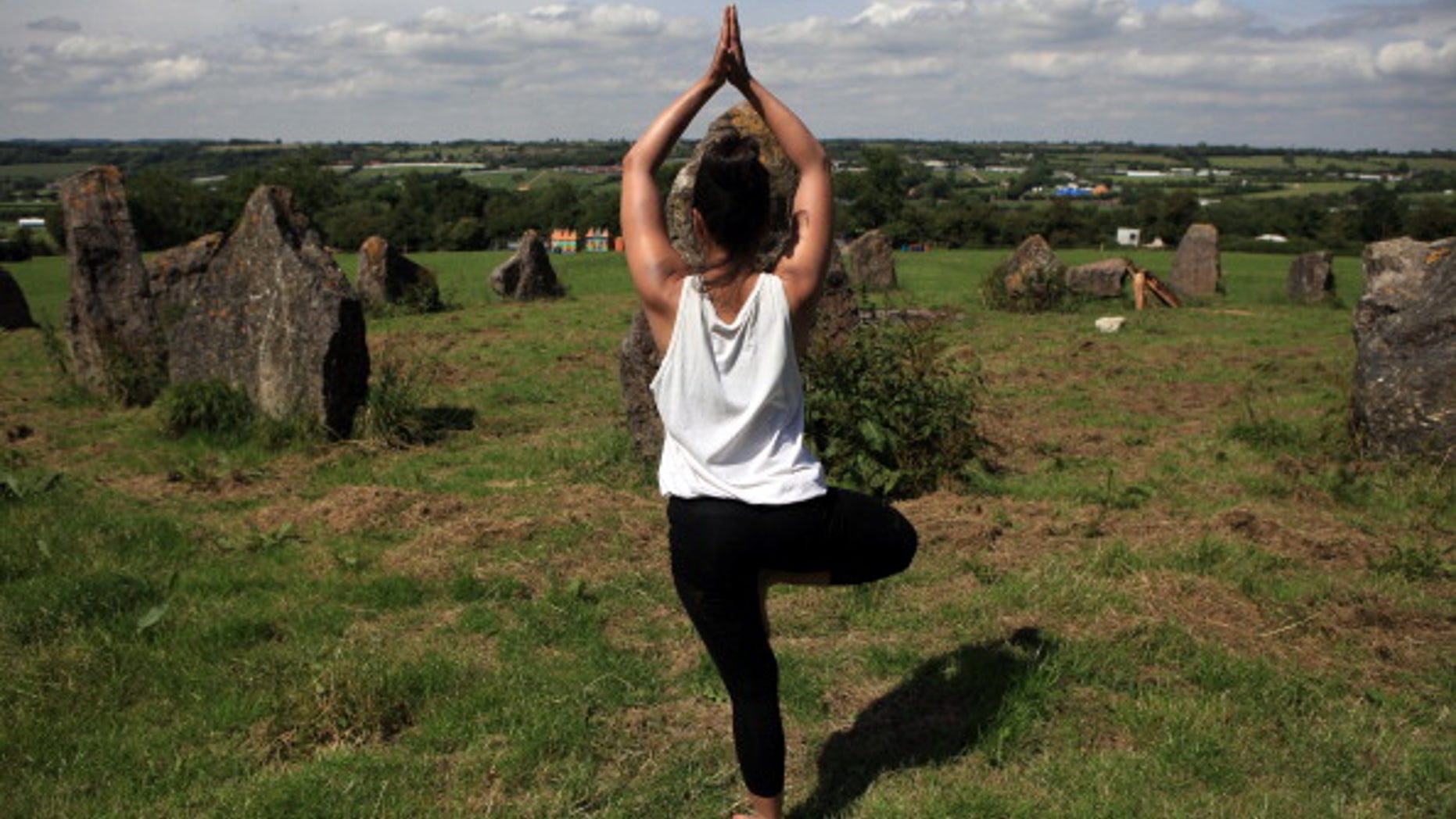 GLASTONBURY, ENGLAND - JUNE 14: A festival worker takes time out to practice yoga in the stone circle at the Glastonbury Festival site at Worthy Farm, in Pilton on June 14, 2011 in Glastonbury, England. The gates open a week tomorrow to the festival which will feature headline acts U2, Coldplay and Beyonce.The festival, which started in 1970 when several hundred hippies paid 1 GBP to watch Marc Bolan, has grown into Europe's largest music festival attracting more than 175,000 people over five days. (Photo by Matt Cardy/Getty Images)