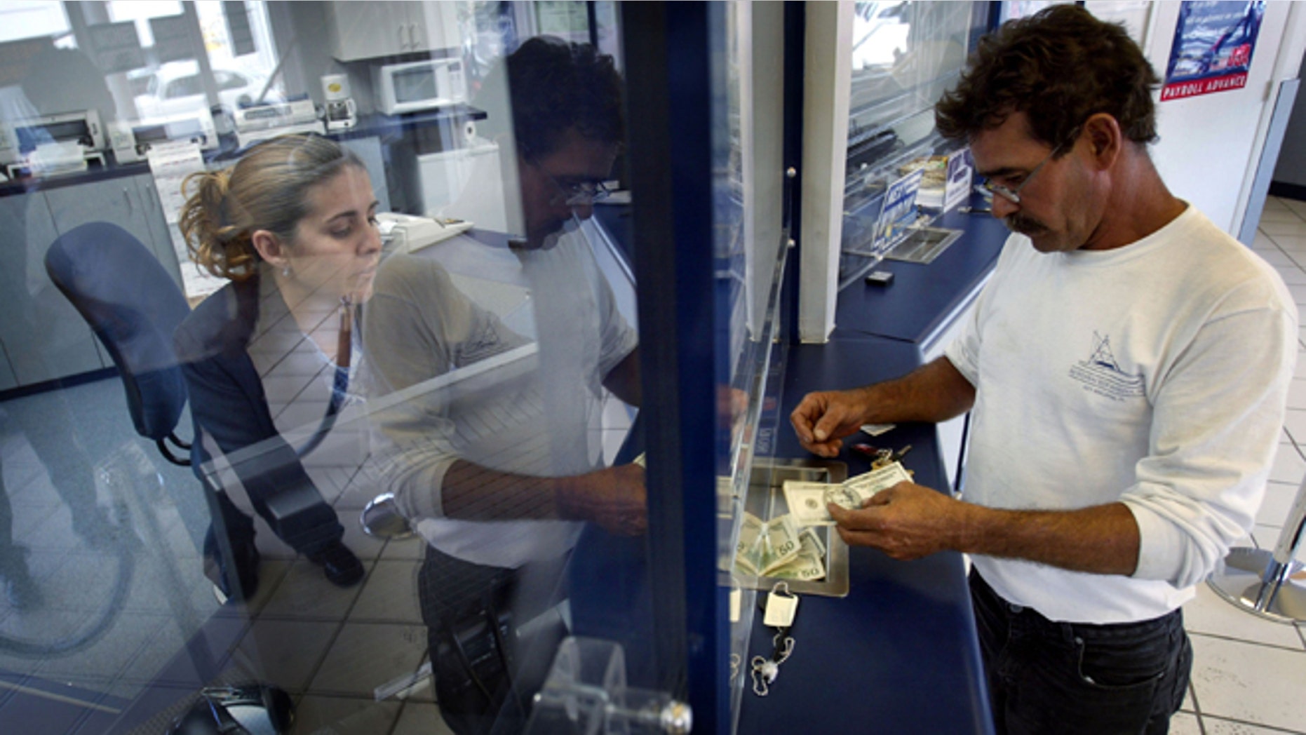 MIAMI - MAY 11: Rachel Garcia takes cash from Ramon Cruz (R) for a $300 wire transfer via Western Union to Cuba, which Cruz left three years ago, the money will be received by his mother still living on the island May 11, 2004 at a Check Cashing USA store in the Little Havana neighborhood in Miami, Florida. The Cuban government announced that many sales in U.S. dollars would be suspended indefinitely. The government blamed the new measure on the Bush Administration's decision last week to tighten trips and cash remittances to the island. (Photo by Joe Raedle/Getty Images)