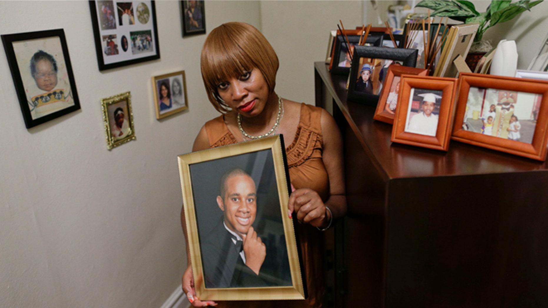 In this June 25, 2014 photo, Tracie Morales stands with a photo of her son, Jamal Polo in New York. Polo committed suicide in May 2012 while jailed on sexual misconduct charges. Investigative documents obtained by The Associated Press on the 11 suicides in New York City jails over the past five years show that in at least nine cases, protocols and safeguards designed to prevent inmates from harming themselves were not followed. (AP Photo/Julie Jacobson)