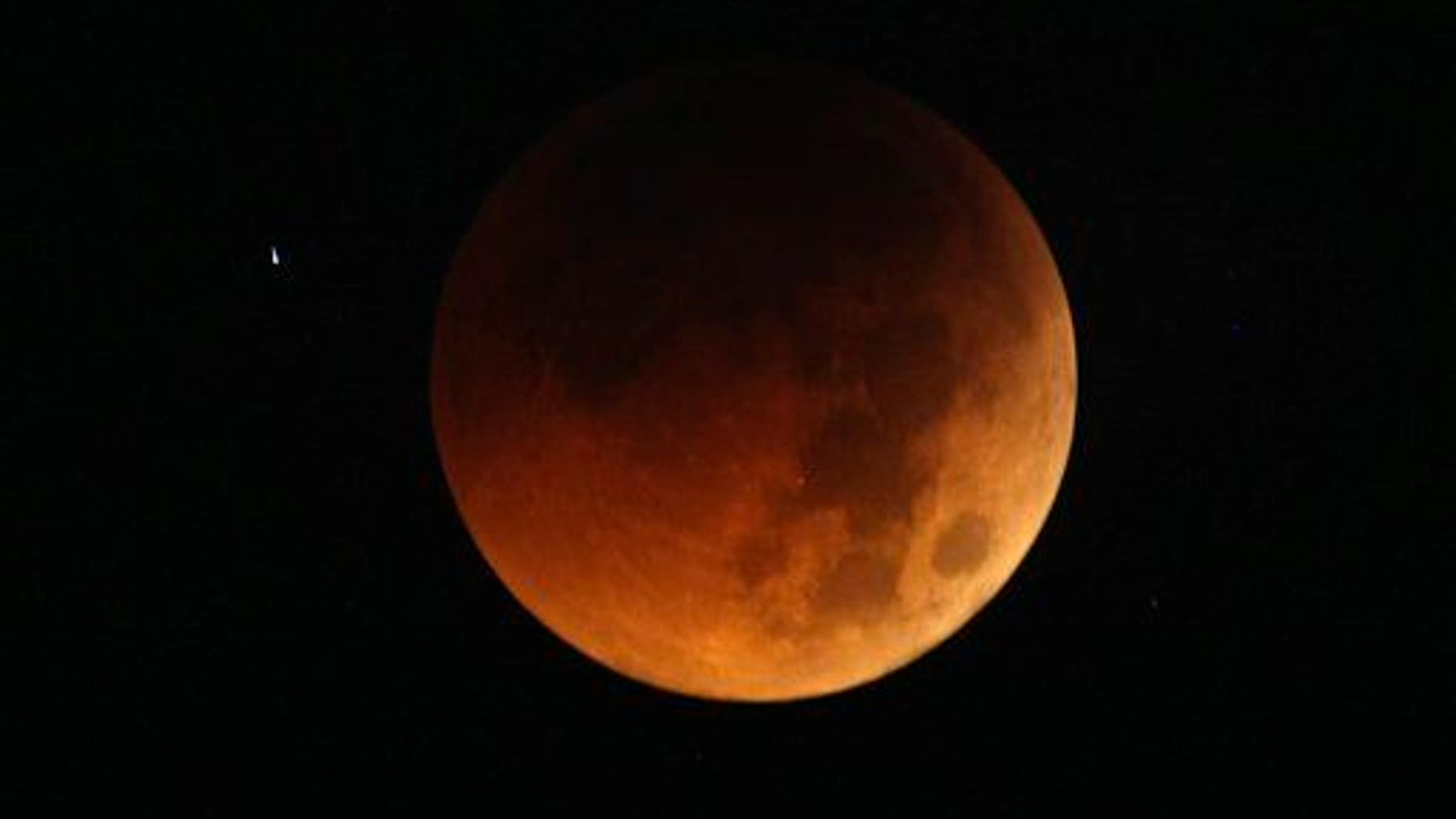 The moon exhibits a deep orange glow as the Earth casts its shadow in a total lunar eclipse as seen in Manila, Philippines, before dawn Thursday June 16, 2011.