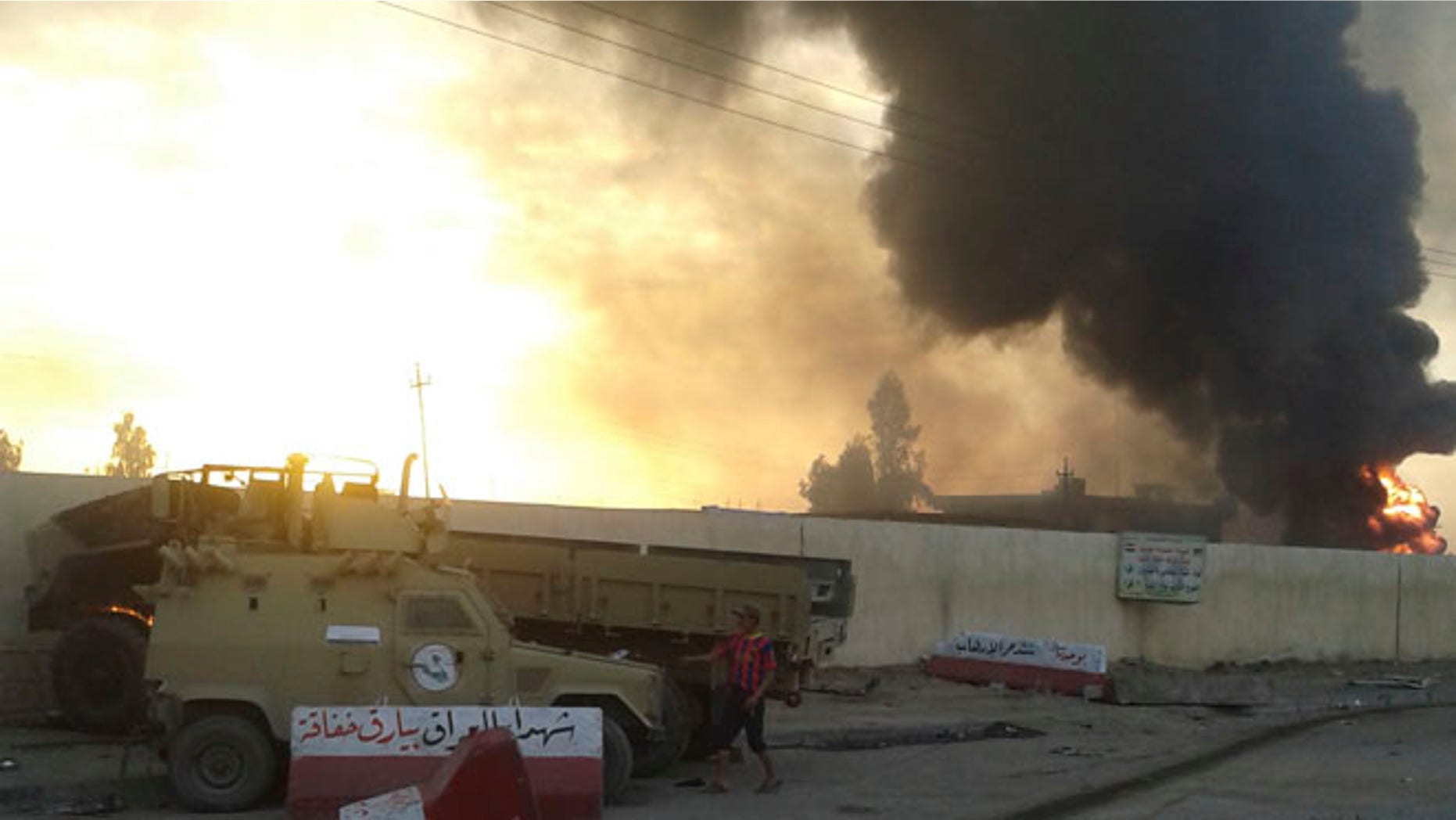 June 10, 2014: A civilian stands near damaged vehicles belonging to Iraqi security forces in the northern Iraq city of Mosul.