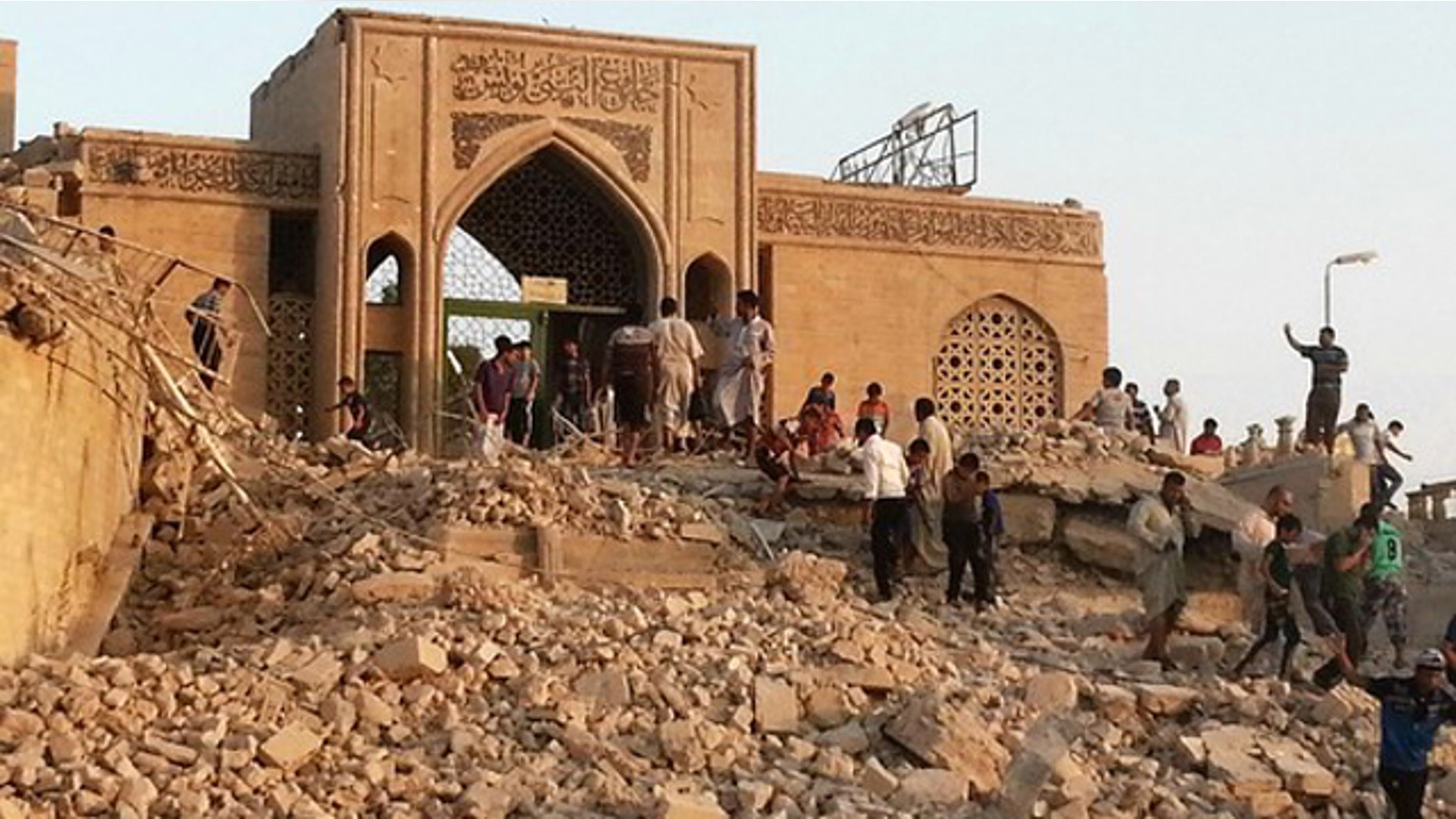 July 25, 2014: Residents of Mosul, Iraq, climb over the ruins of the Nabi Younes Mosque one day after it was destroyed by ISIS (Reuters)